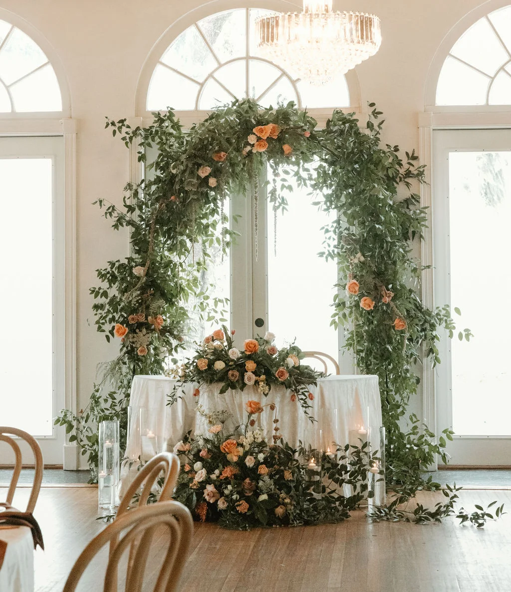 Elegant wedding reception decor with floral arch and candles