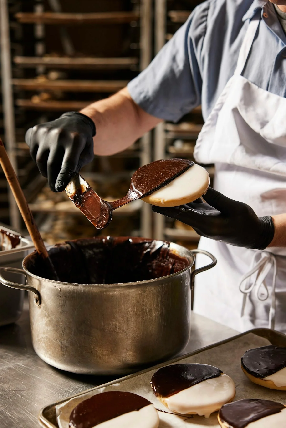 Baker glazing black and white cookies in a professional kitchen