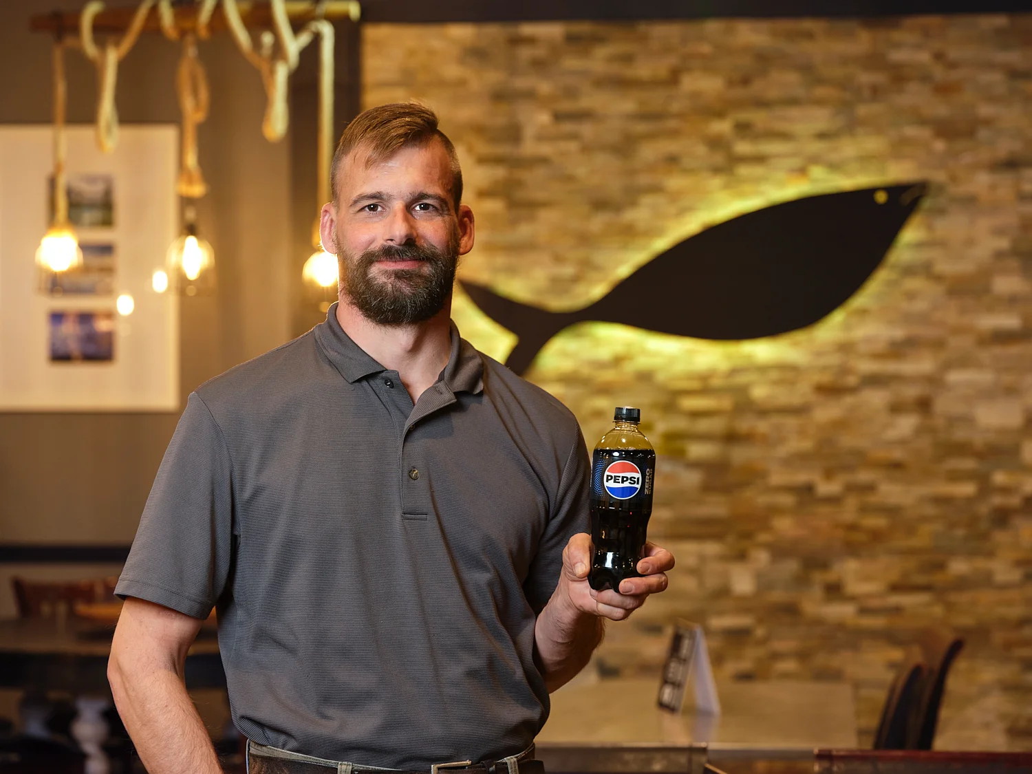Restaurant staff holding a bottle of Pepsi in a cozy dining area