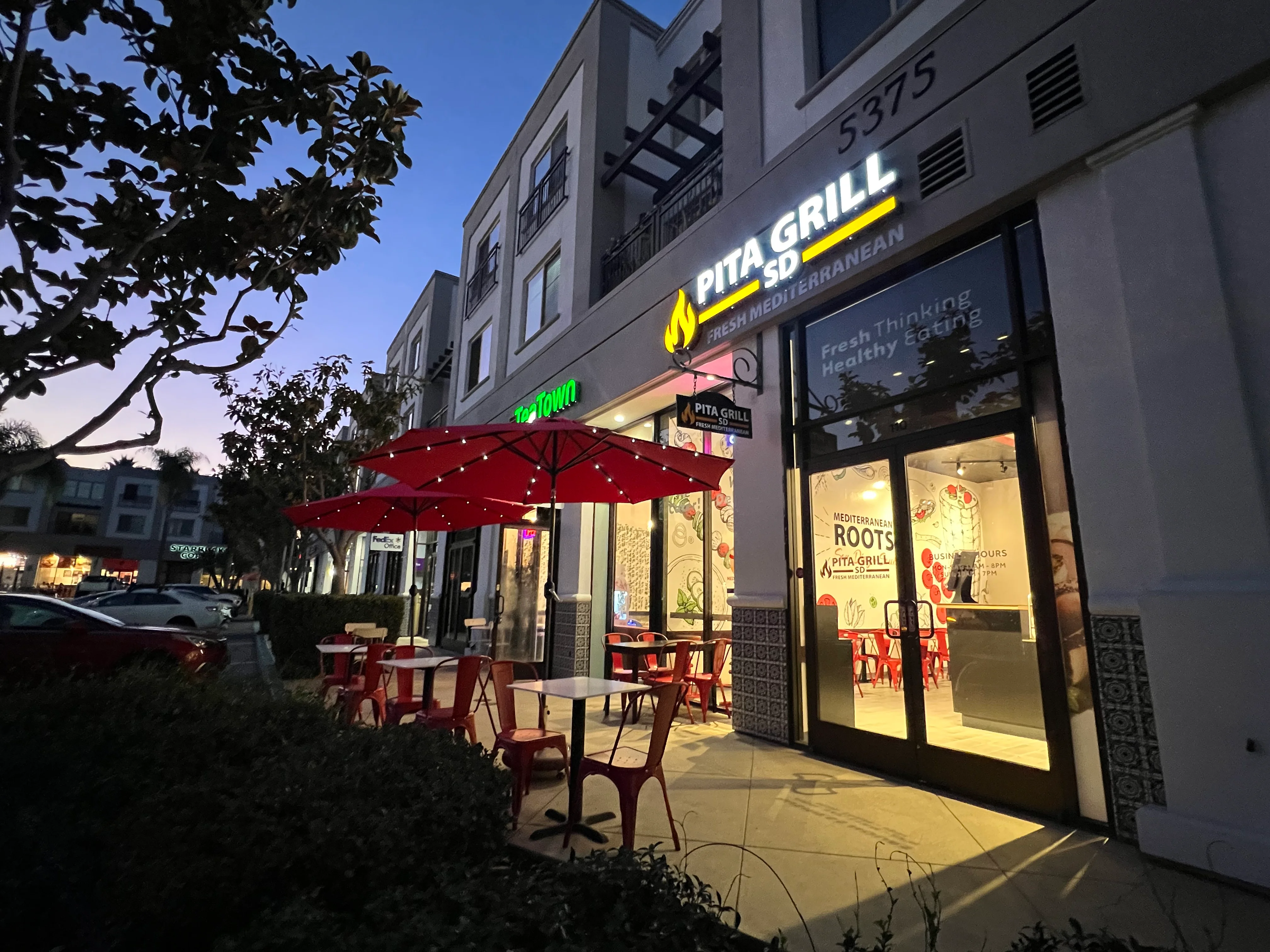 Exterior view of Pita Grill restaurant at dusk with outdoor seating