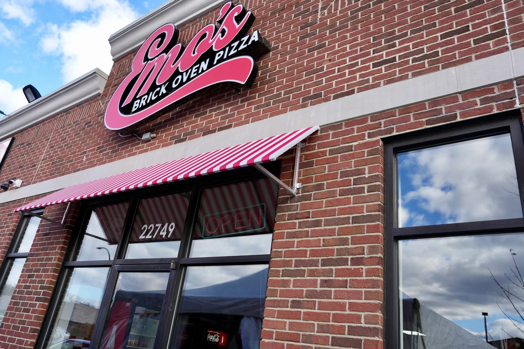 Emo's Brick Oven Pizza restaurant exterior with striped awning