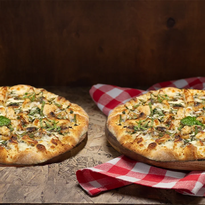 Two delicious pizzas with fresh toppings on a rustic wooden table