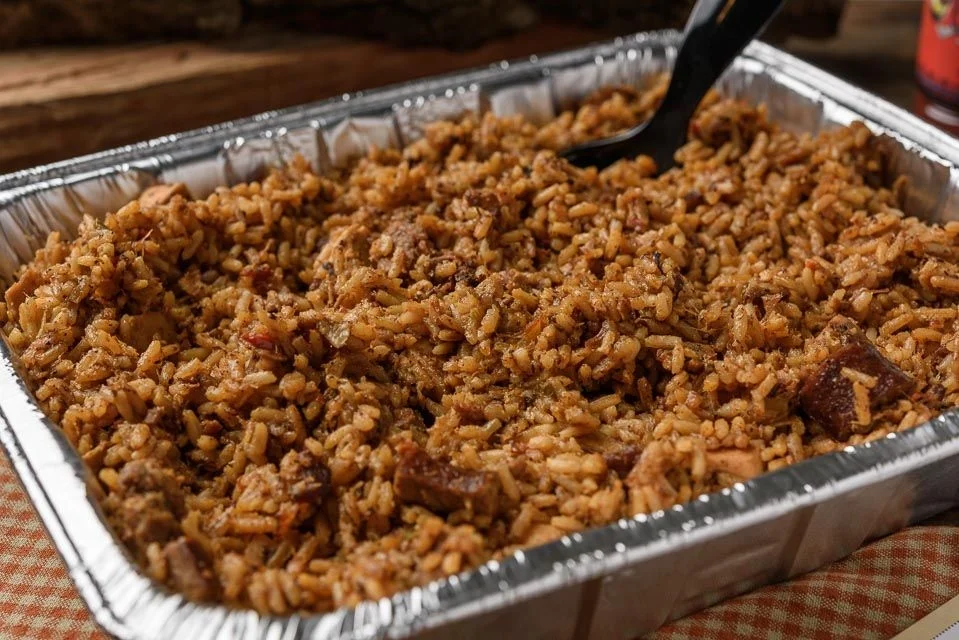 Catering pan of BBQ jambalaya from VooDoo BBQ in Pensacola, showcasing a Cajun-style side dish option.