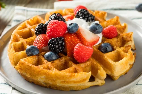 Belgian waffle topped with fresh berries and whipped cream