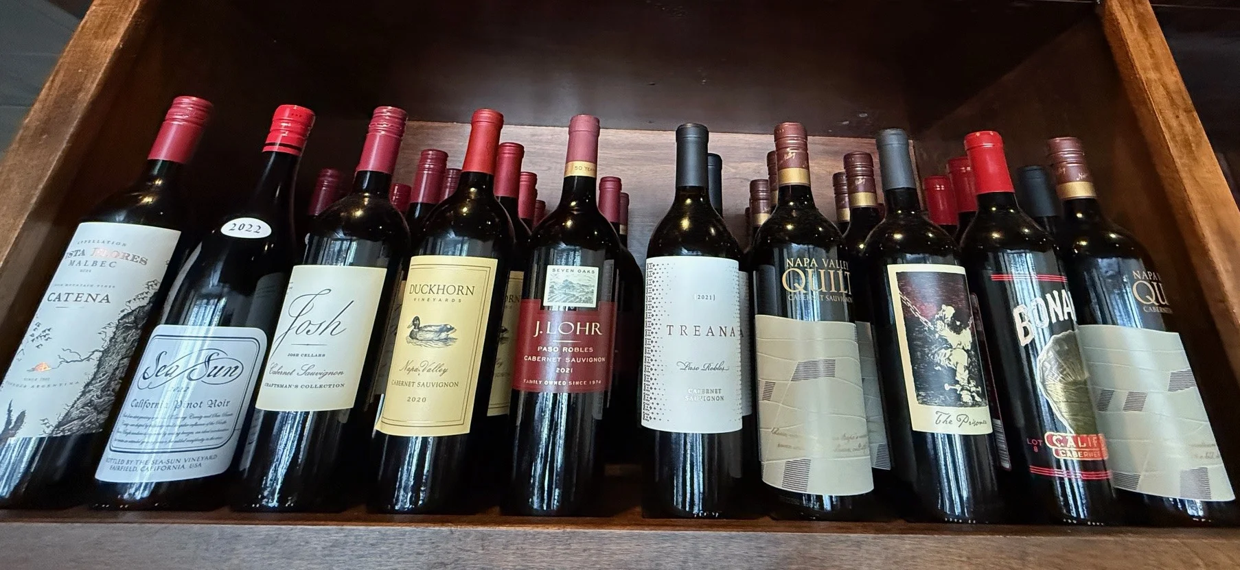 Wine selection displayed on wooden shelves in a cozy bar