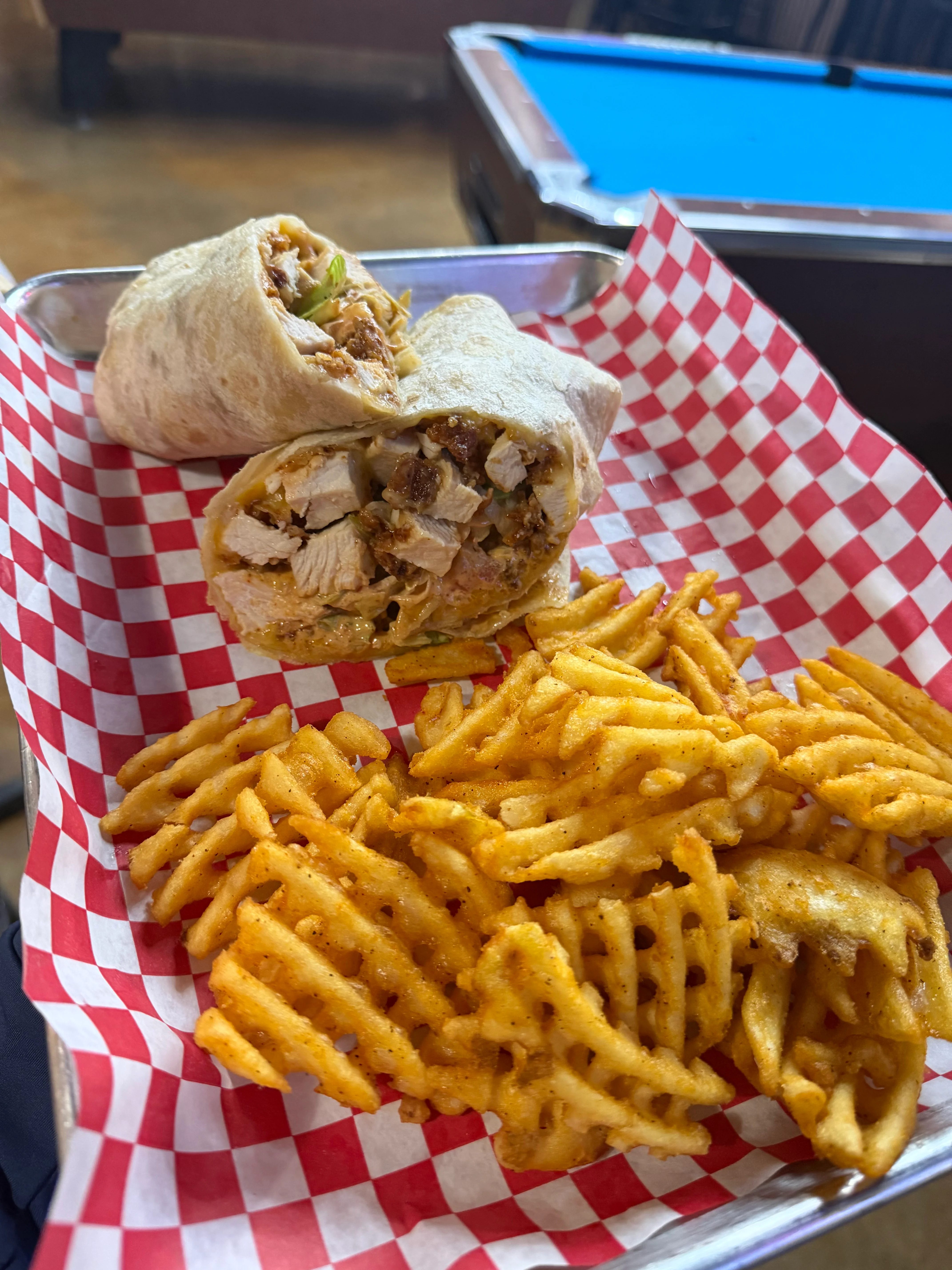 Grilled chicken wrap with waffle fries in a casual dining setting