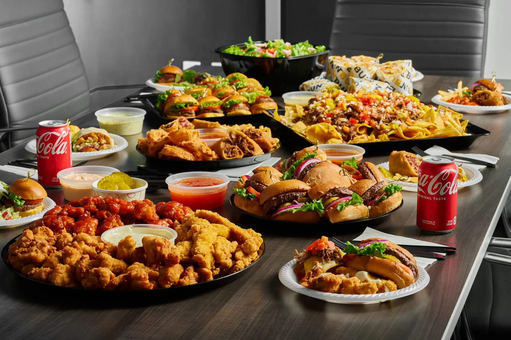 Assorted American party platters with burgers, wings, and nachos