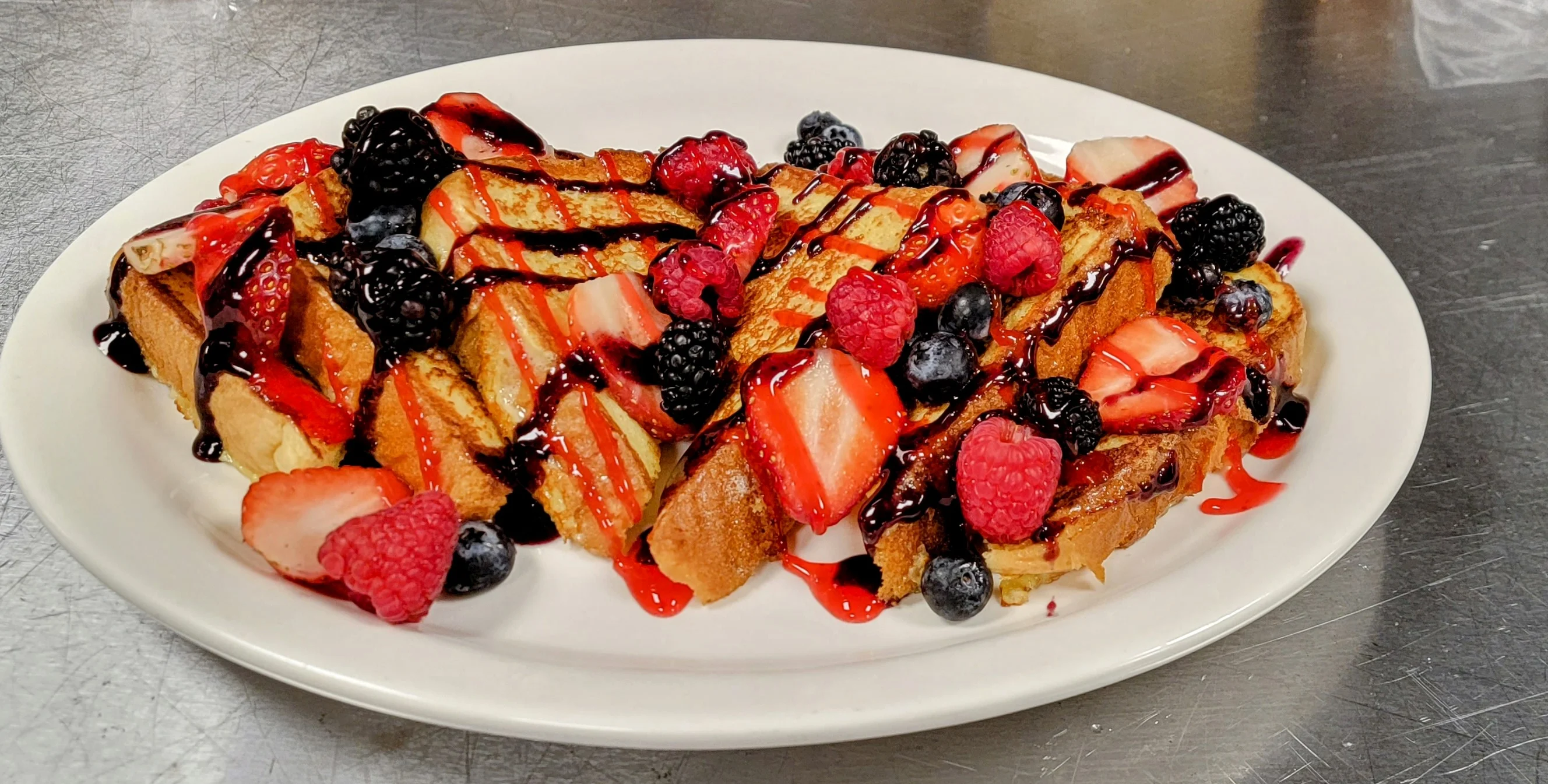 French toast topped with mixed berries and chocolate drizzle