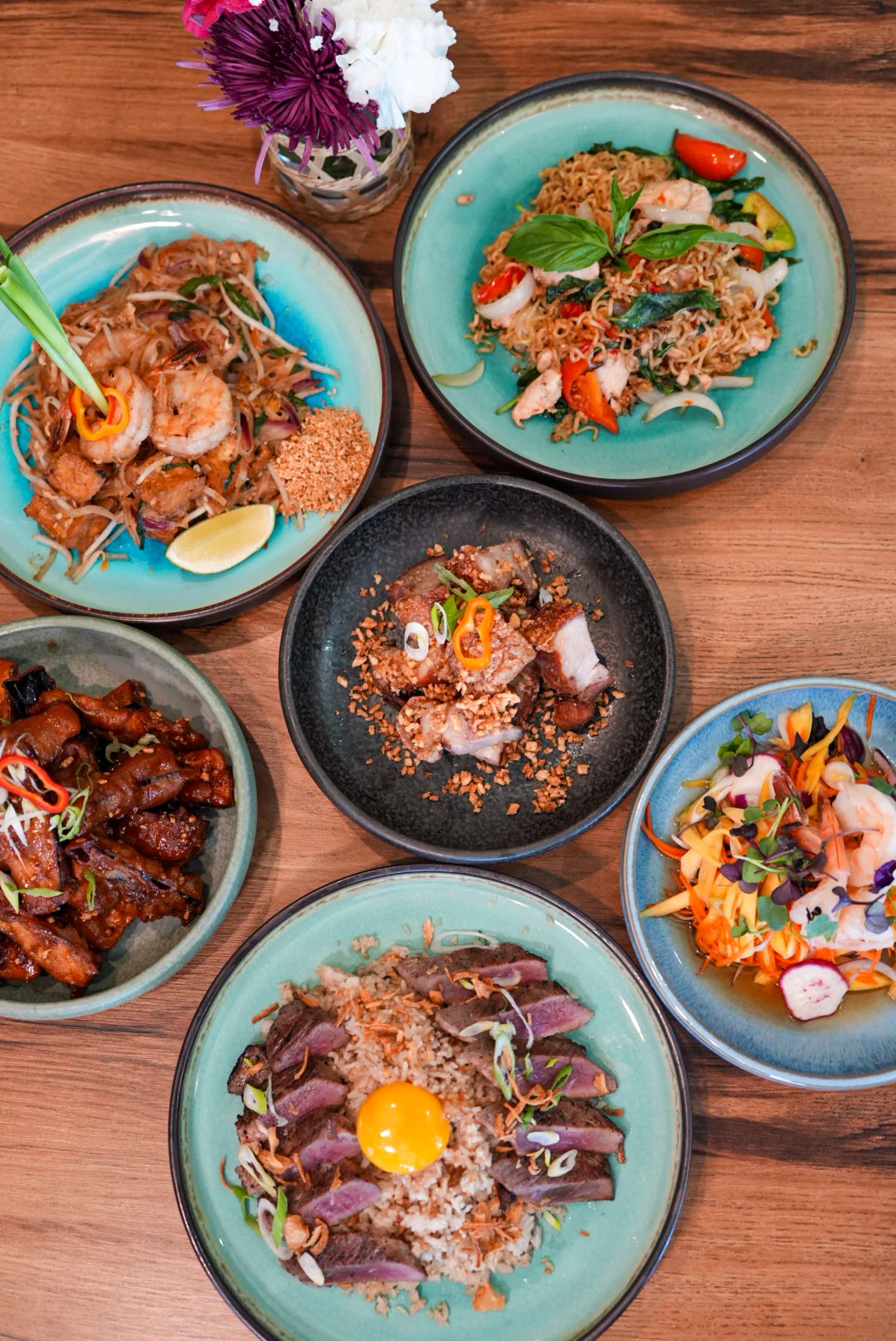 Assorted Asian dishes including stir-fried noodles and grilled meats