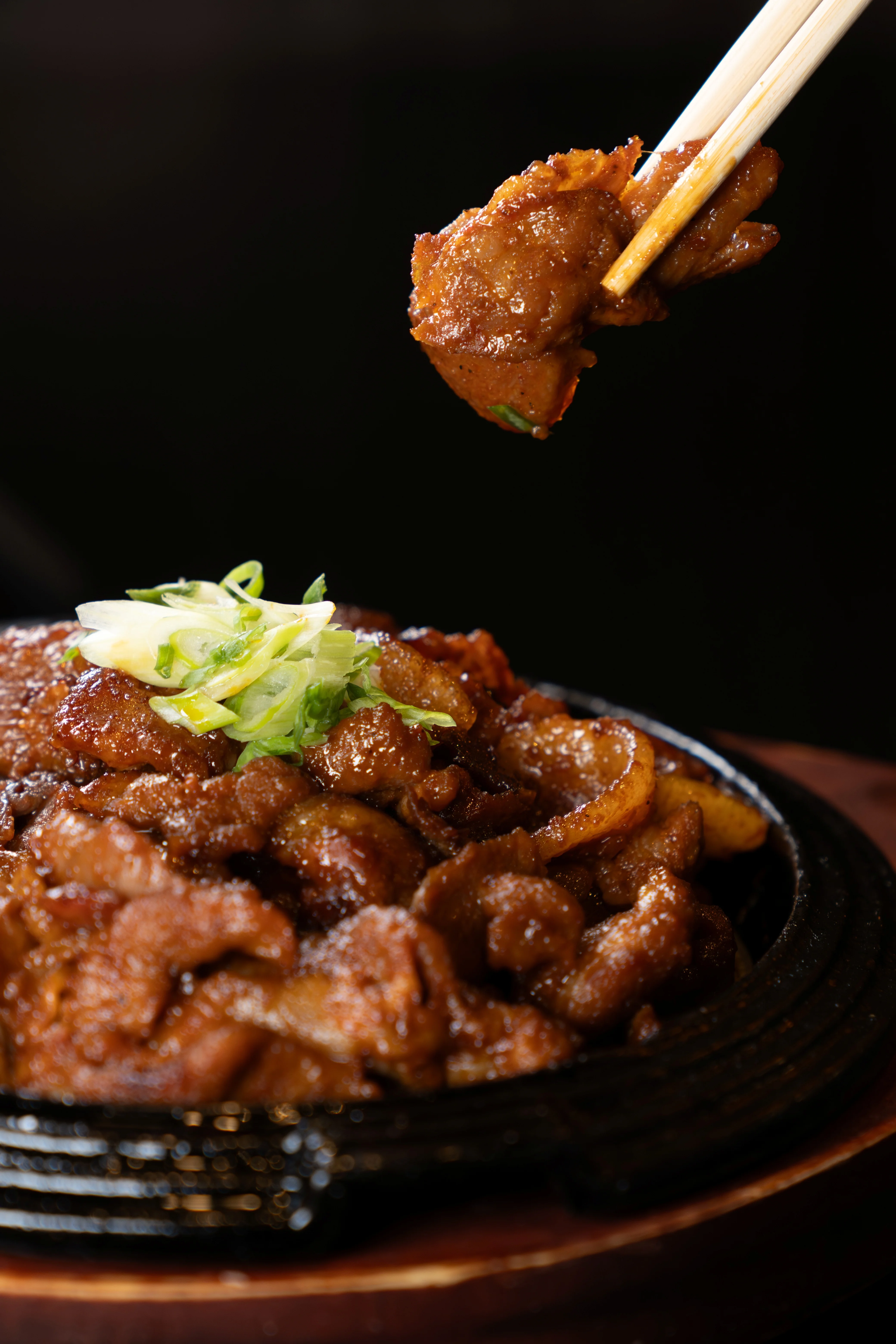 Delicious sizzling beef dish with green onions served on a hot plate.