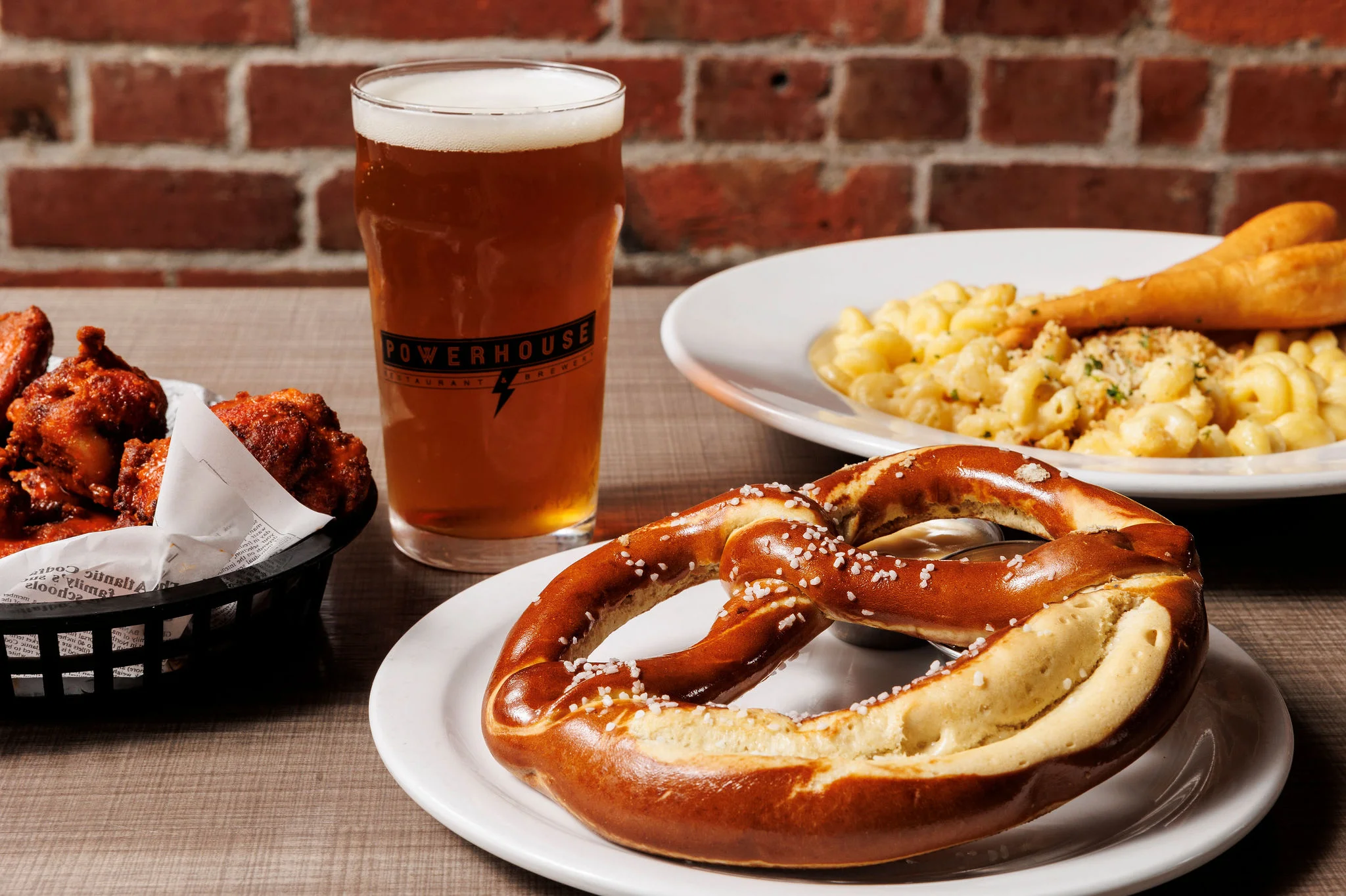 Soft pretzel served with beer and wings in a casual dining setting