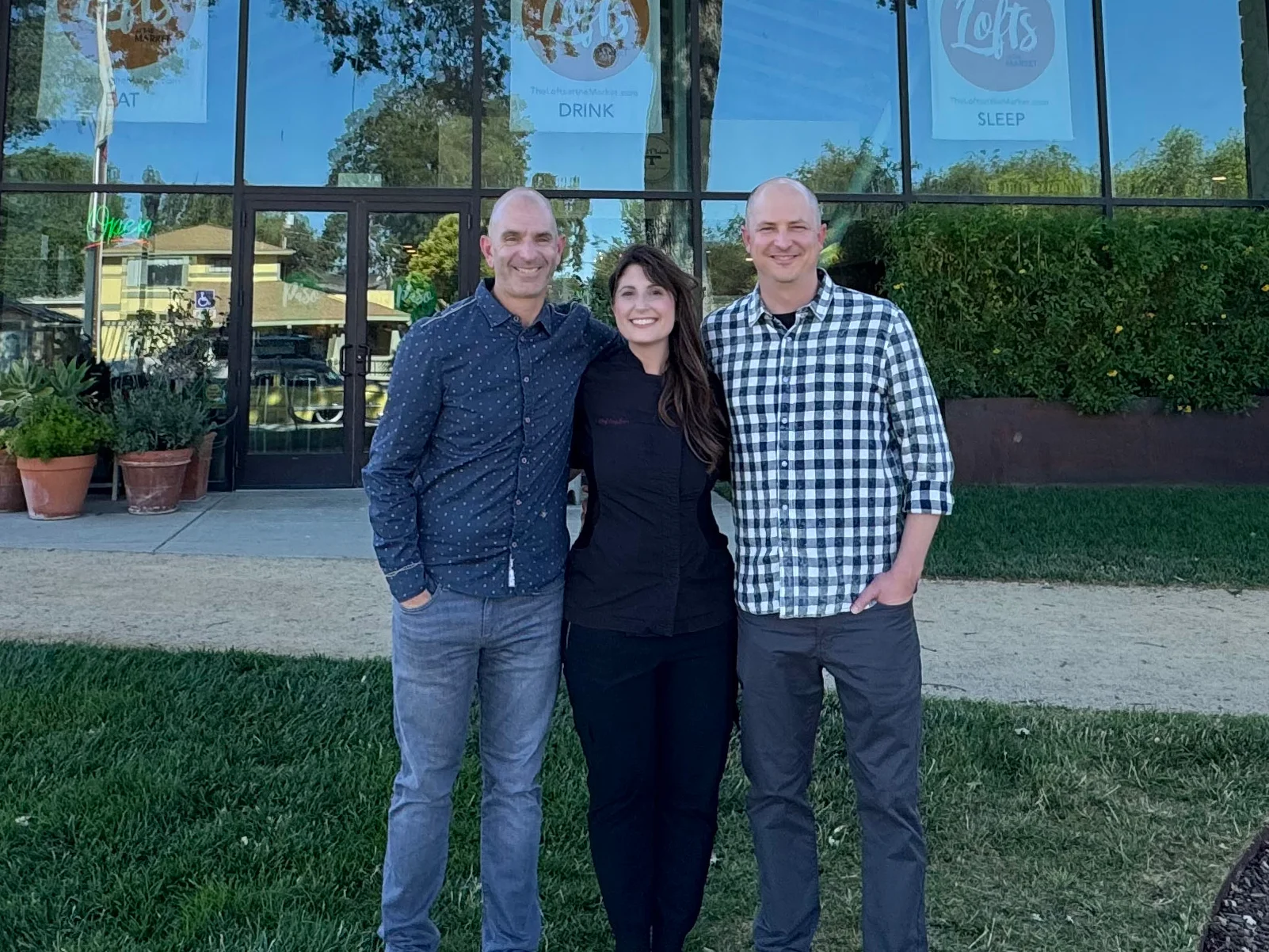 Group of three people in front of a modern restaurant building