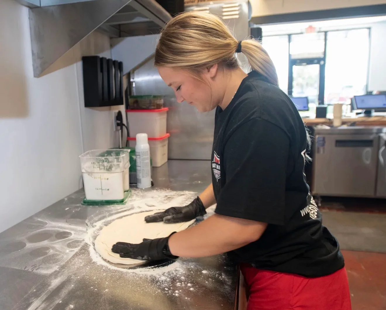 Pizza maker hand-stretching dough in a professional restaurant kitchen