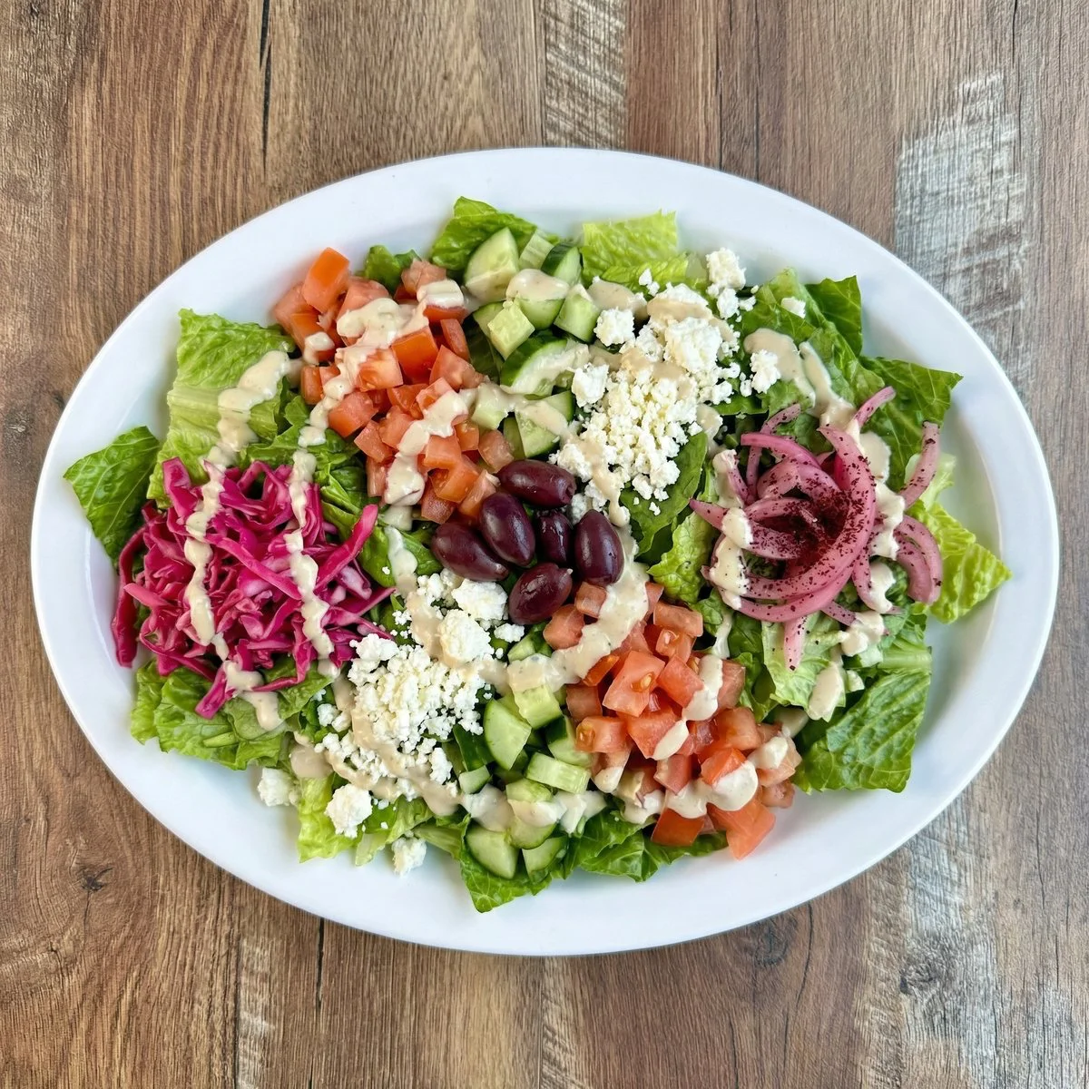 Fresh salad with mixed greens, tomatoes, and dressing in a bowl.