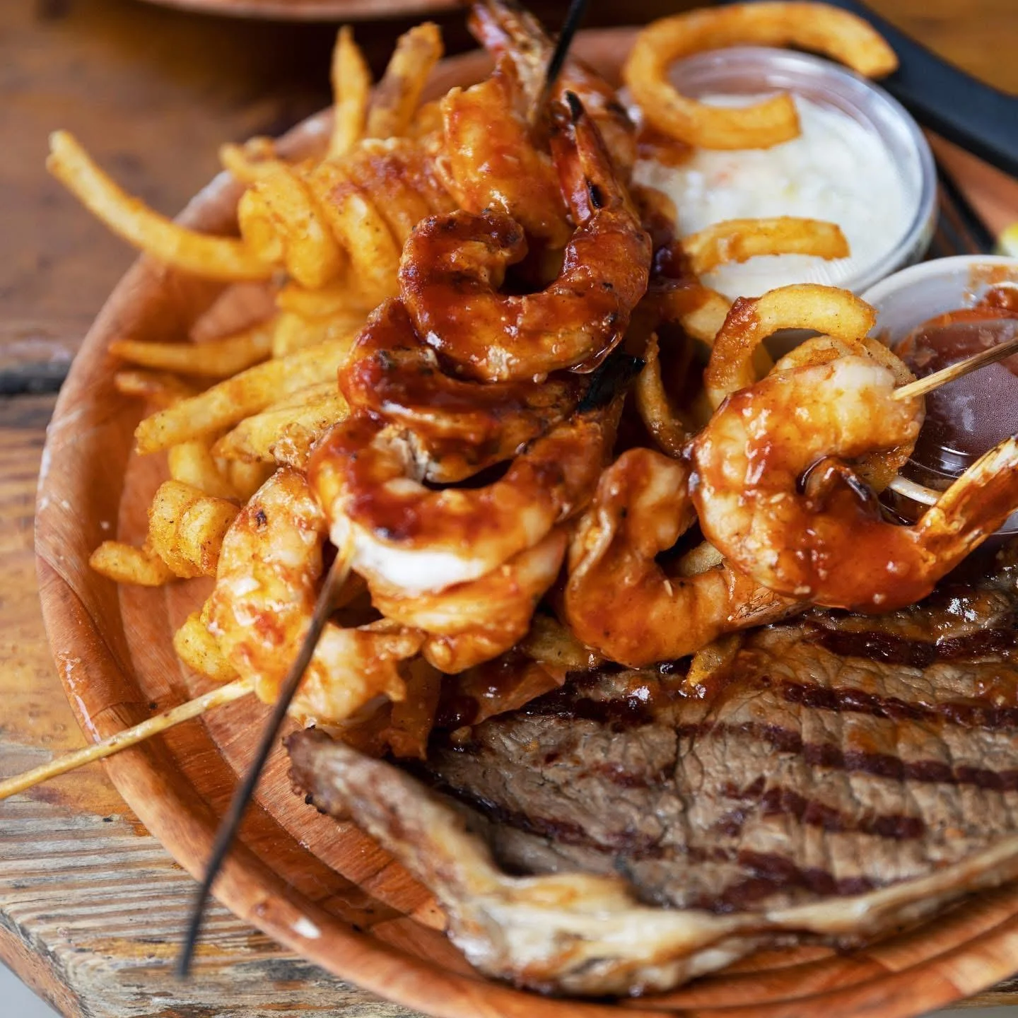 Grilled steak and barbecue shrimp served with seasoned fries at Tarks of Dania in Dania Beach, Florida