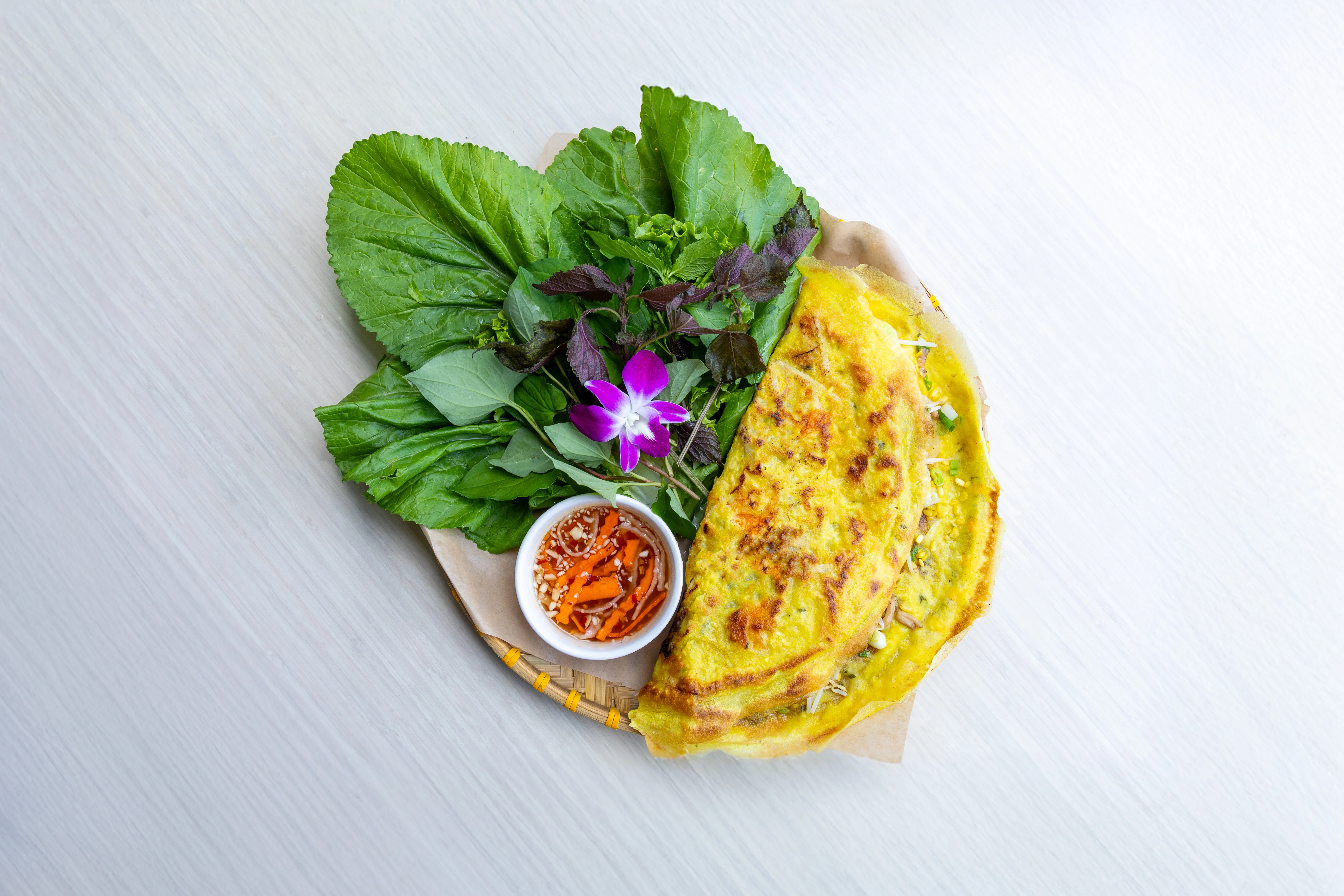 Vietnamese banh xeo with fresh herbs and dipping sauce