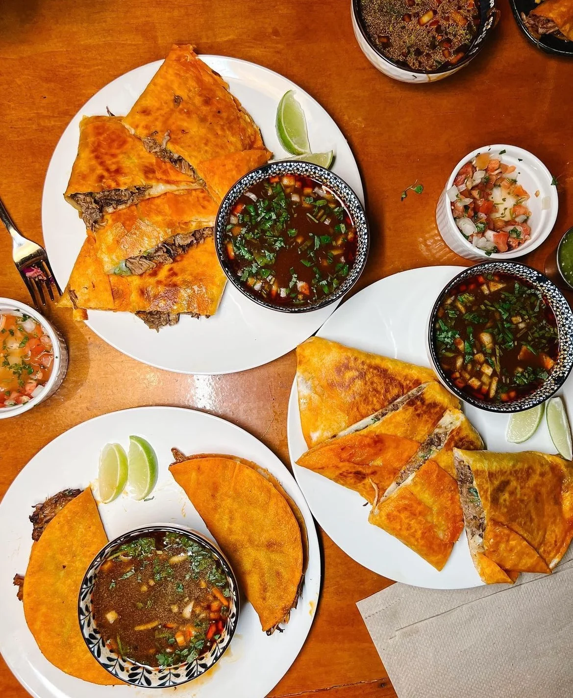 Delicious Mexican quesabirria tacos with consommé and fresh toppings