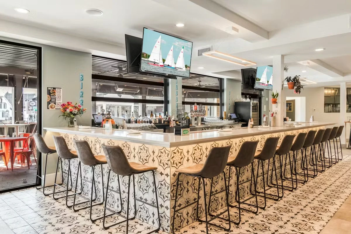 Modern bar interior with seating and TVs displaying sailboats.
