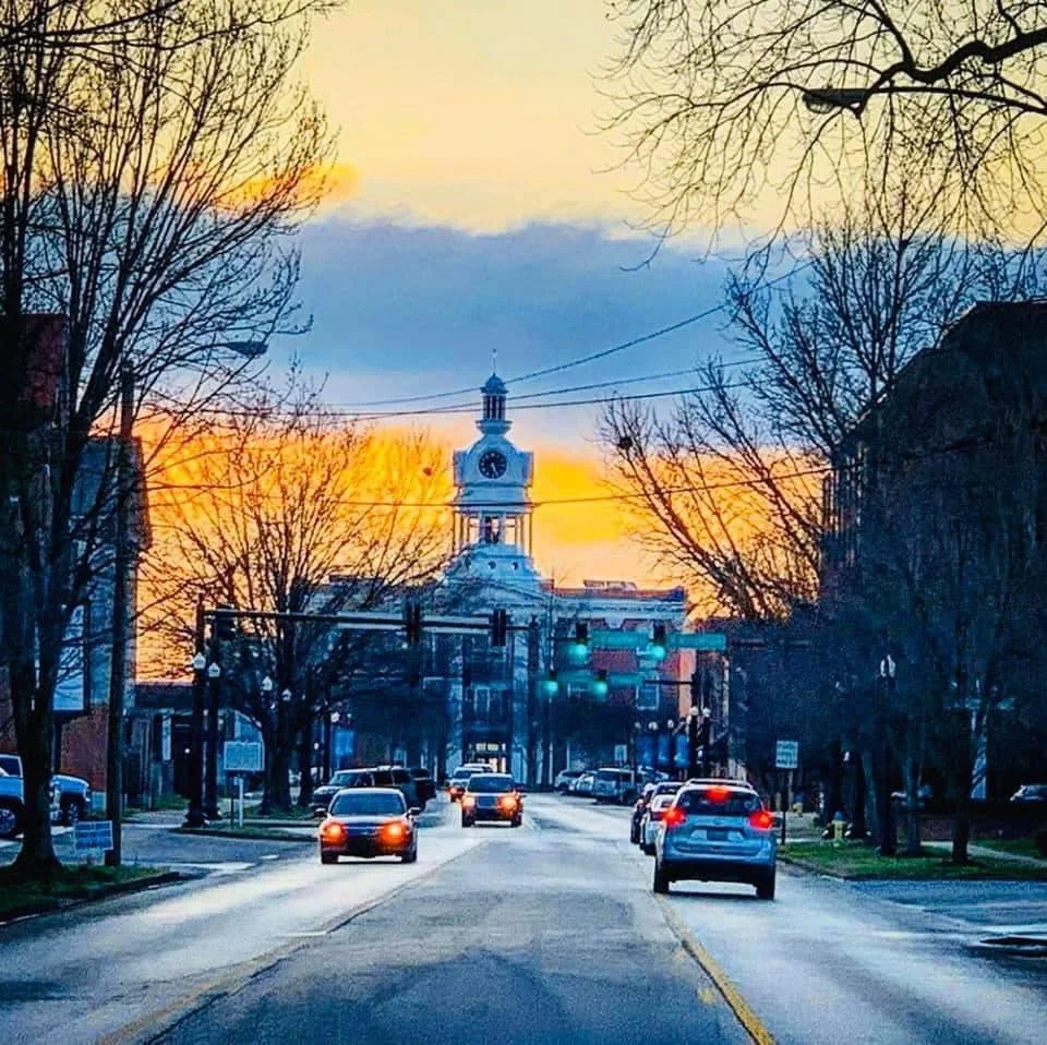 Scenic view of a town square at sunset with a clock tower