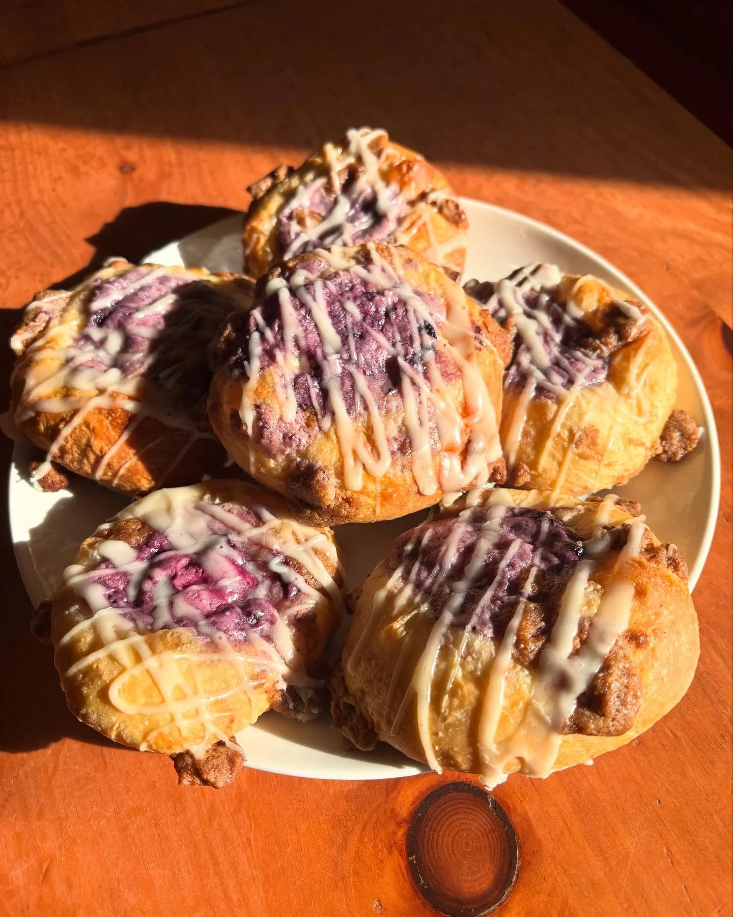 A plate featuring several delicious pastries topped with a berry filling and a drizzle of icing.