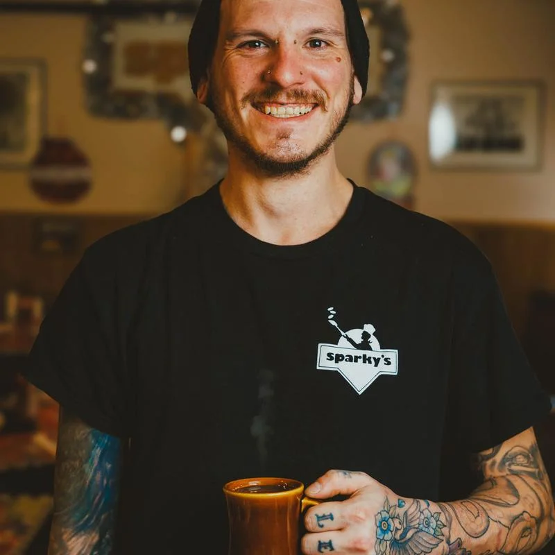 Smiling barista holding a steaming mug in a cozy café
