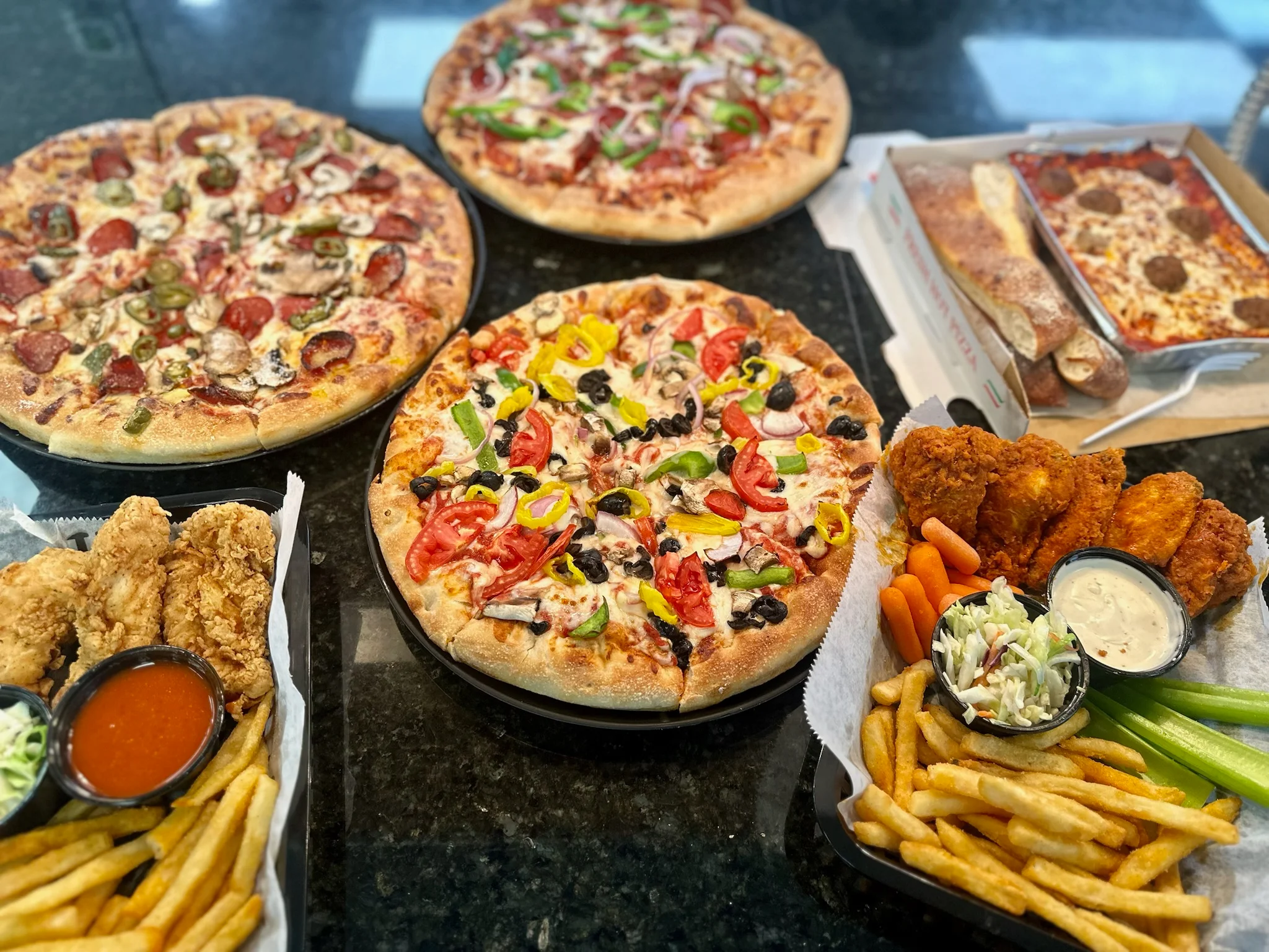 Assorted pizzas and fried chicken platter in a casual dining setting