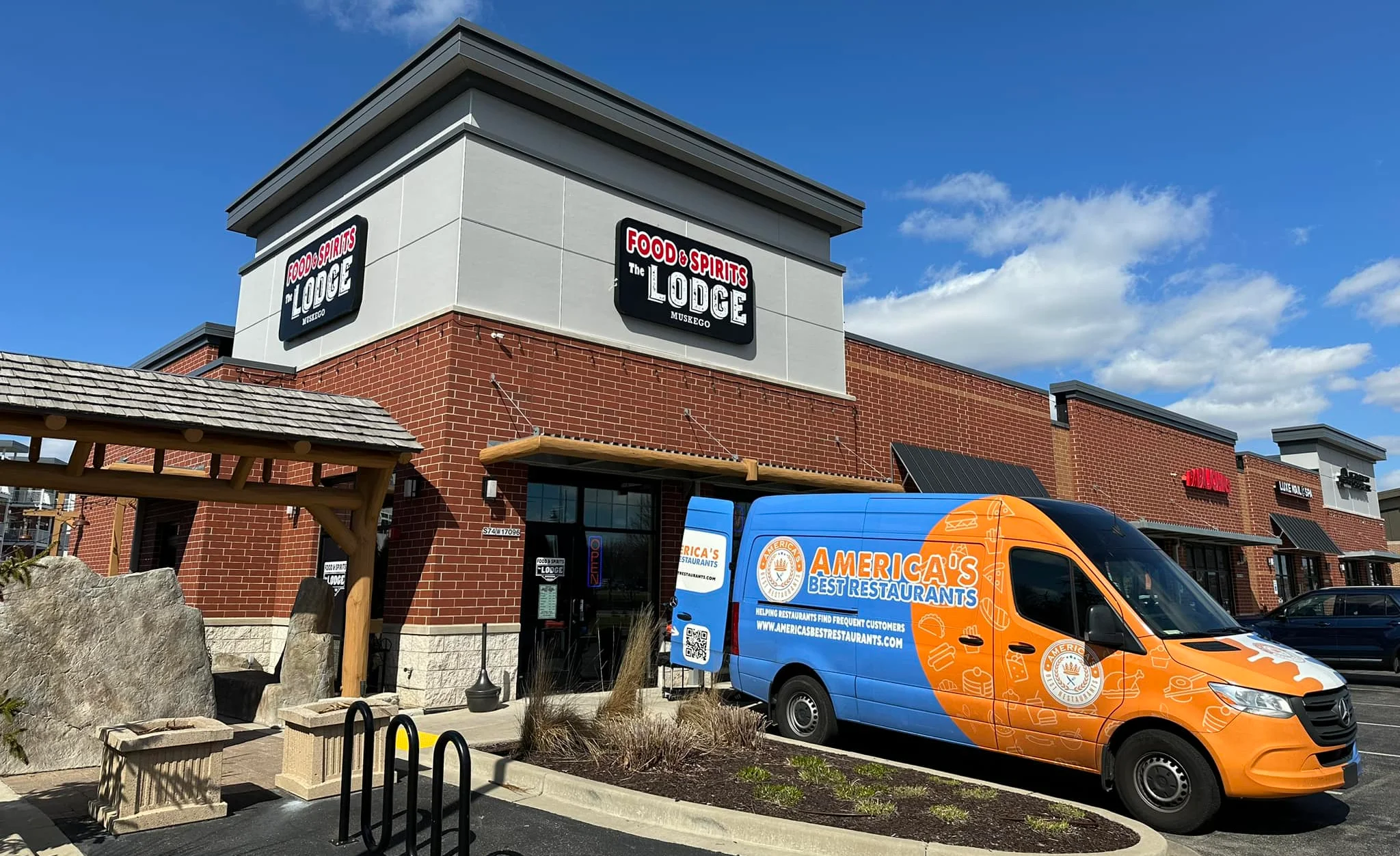 Exterior view of Food & Spirits Lodge restaurant with a delivery van