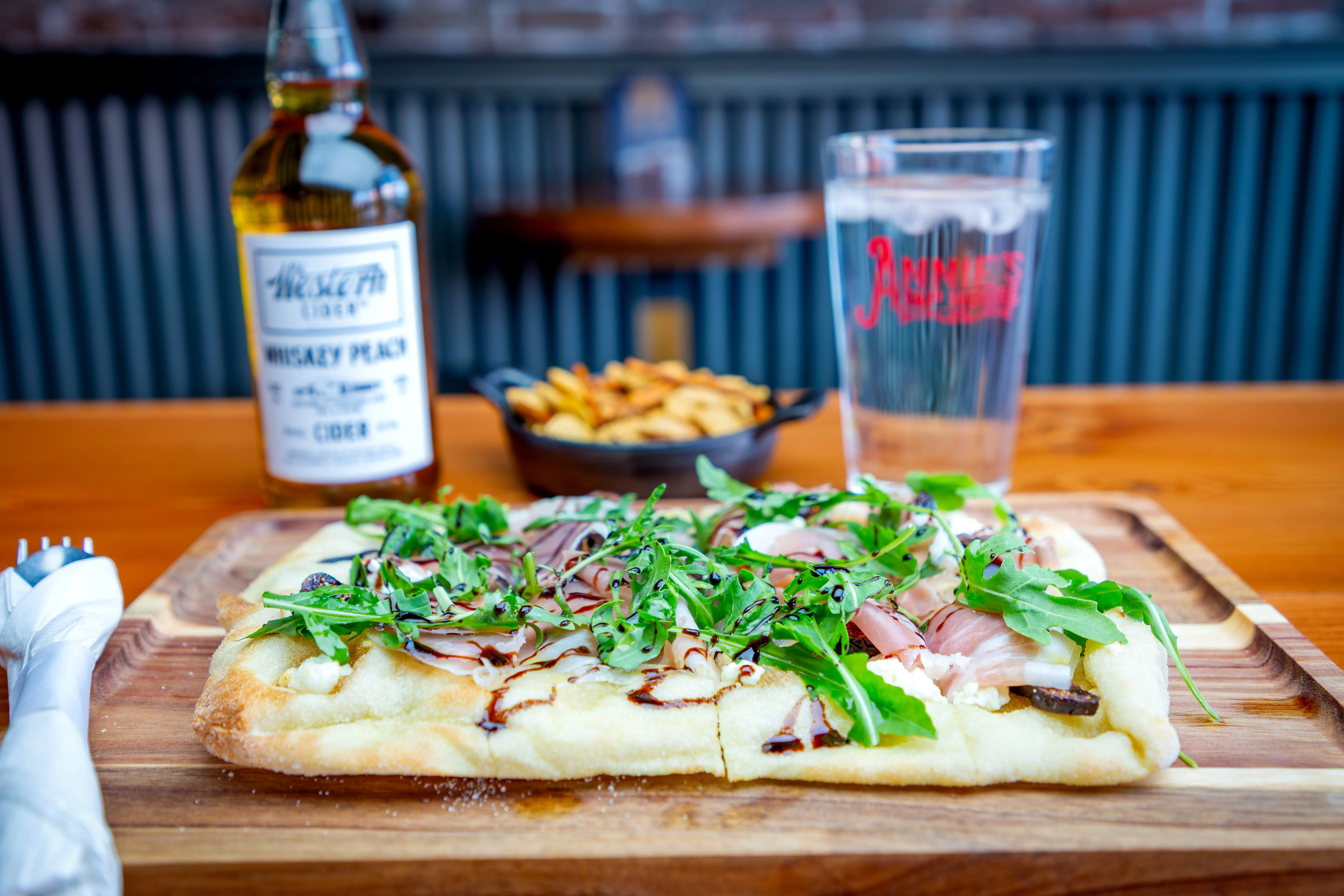 Flatbread topped with prosciutto and arugula in a cozy restaurant setting