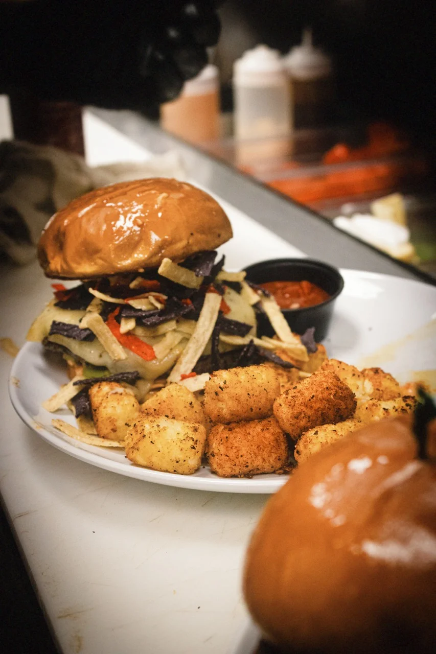 B-Side Coffee Bar Santa Fe Burger with a 7oz patty, topped with pepper jack cheese, avocado, tortilla strips, pico de gallo, and chipotle mayo, served with crispy tater tots in Huber Heights, Ohio.