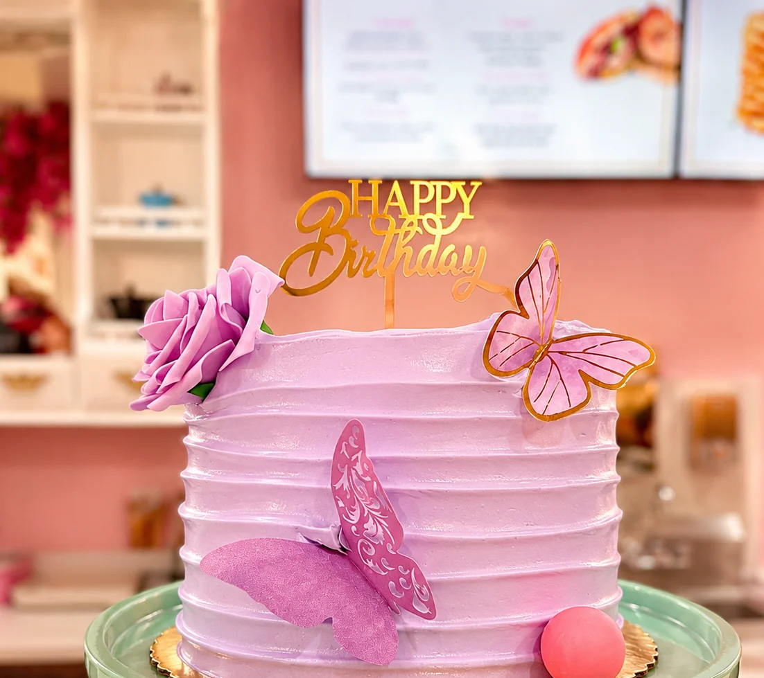 Elegant birthday cake with purple frosting and decorative butterflies