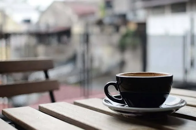 Cup of coffee on a wooden table with a blurred urban background