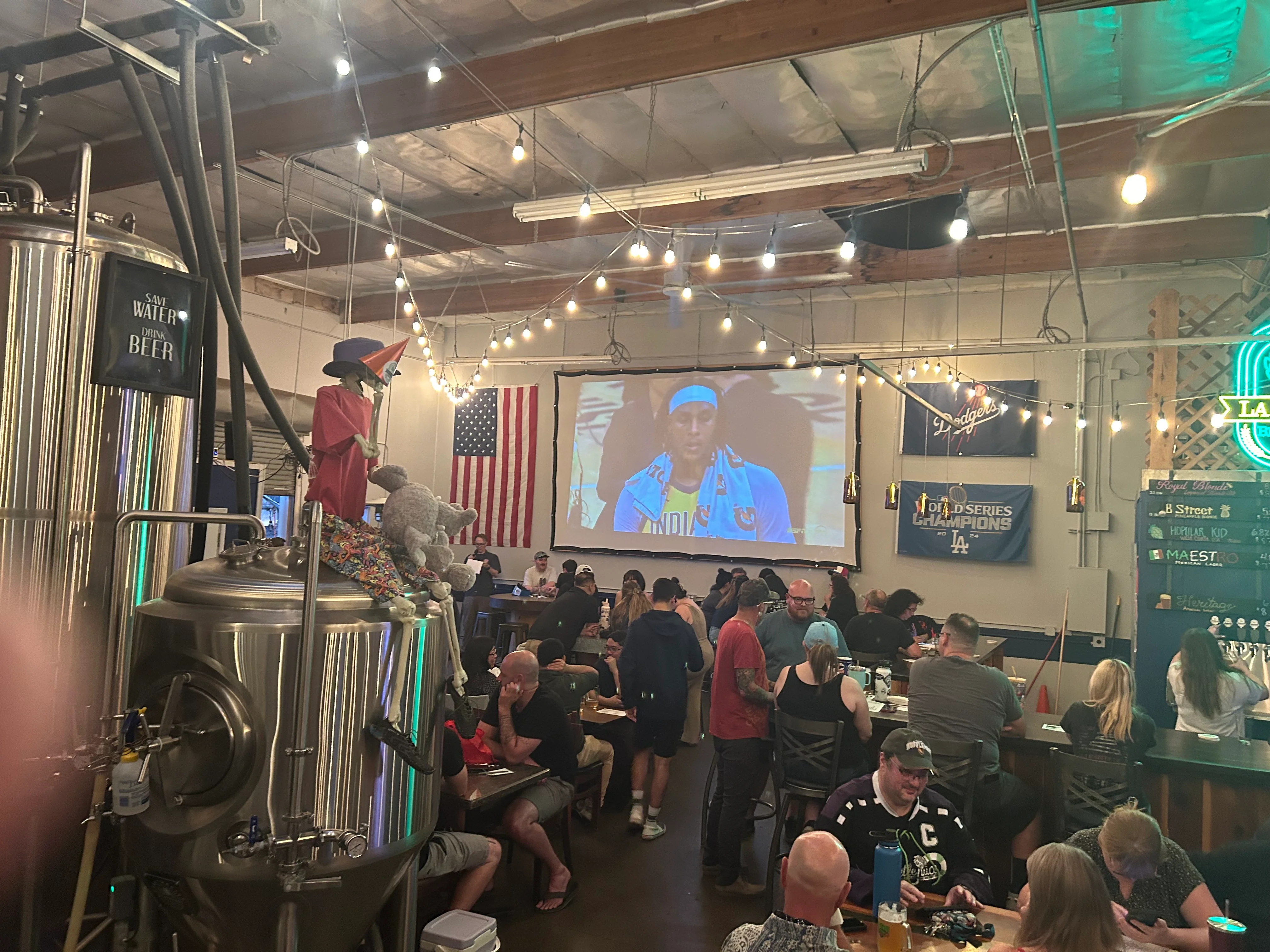 Lively brewery interior with patrons enjoying a game on a large screen