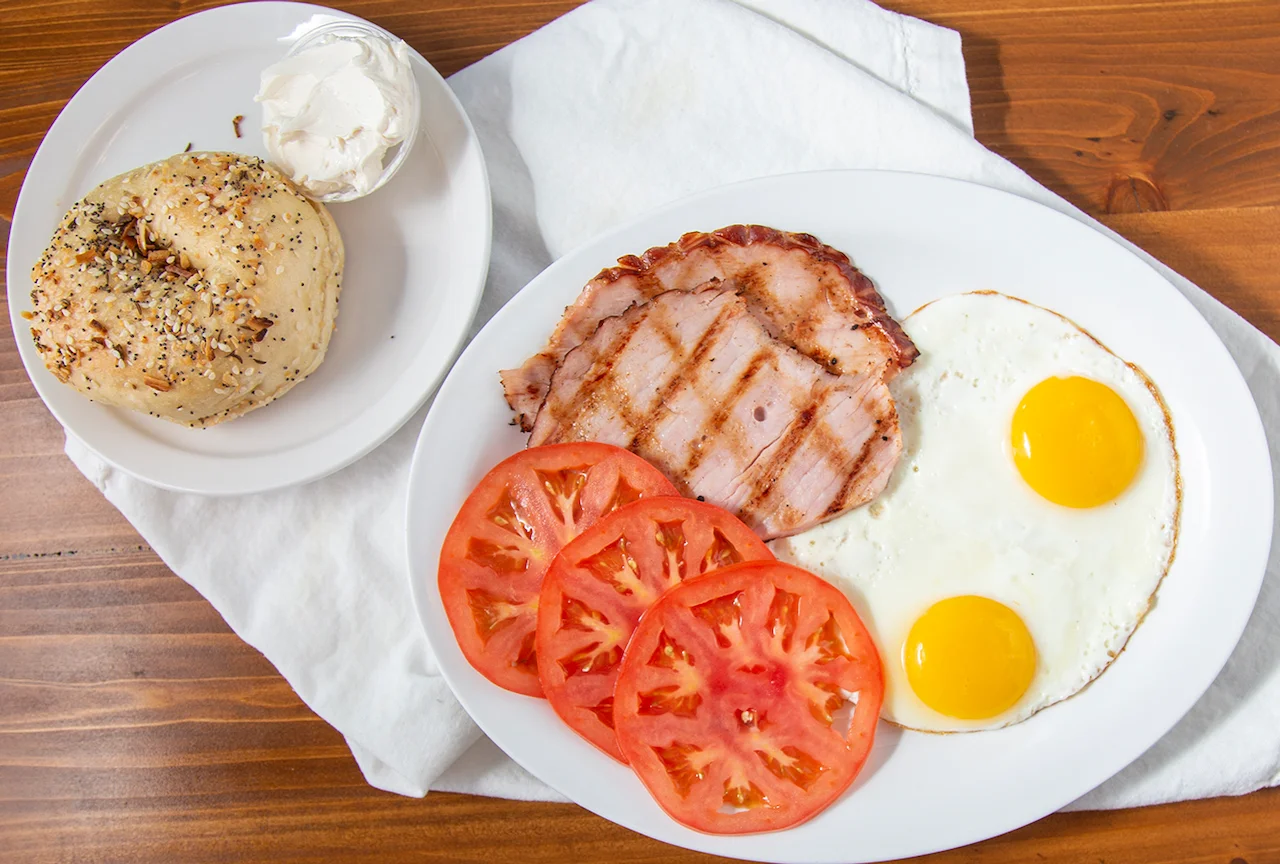 Classic American breakfast with eggs, ham, and bagel