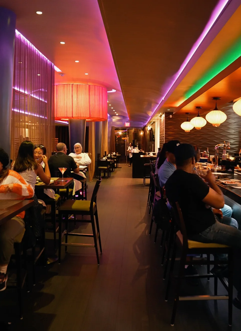 Interior of a modern restaurant with colorful lighting and patrons dining.