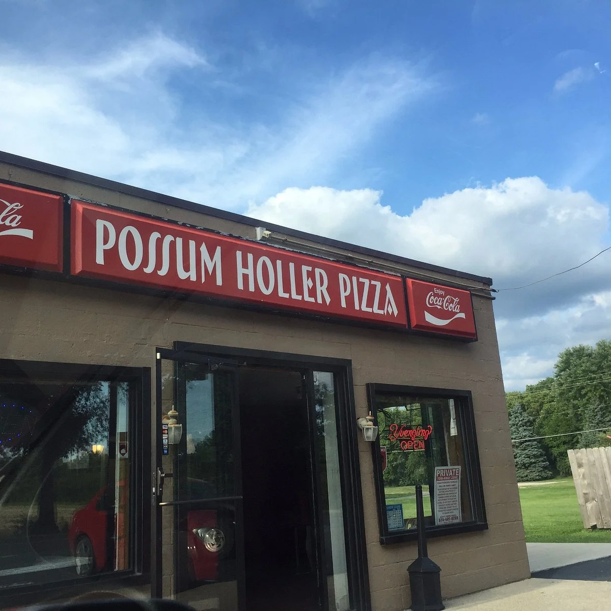 Exterior of Possum Holler Pizza restaurant with a blue sky.