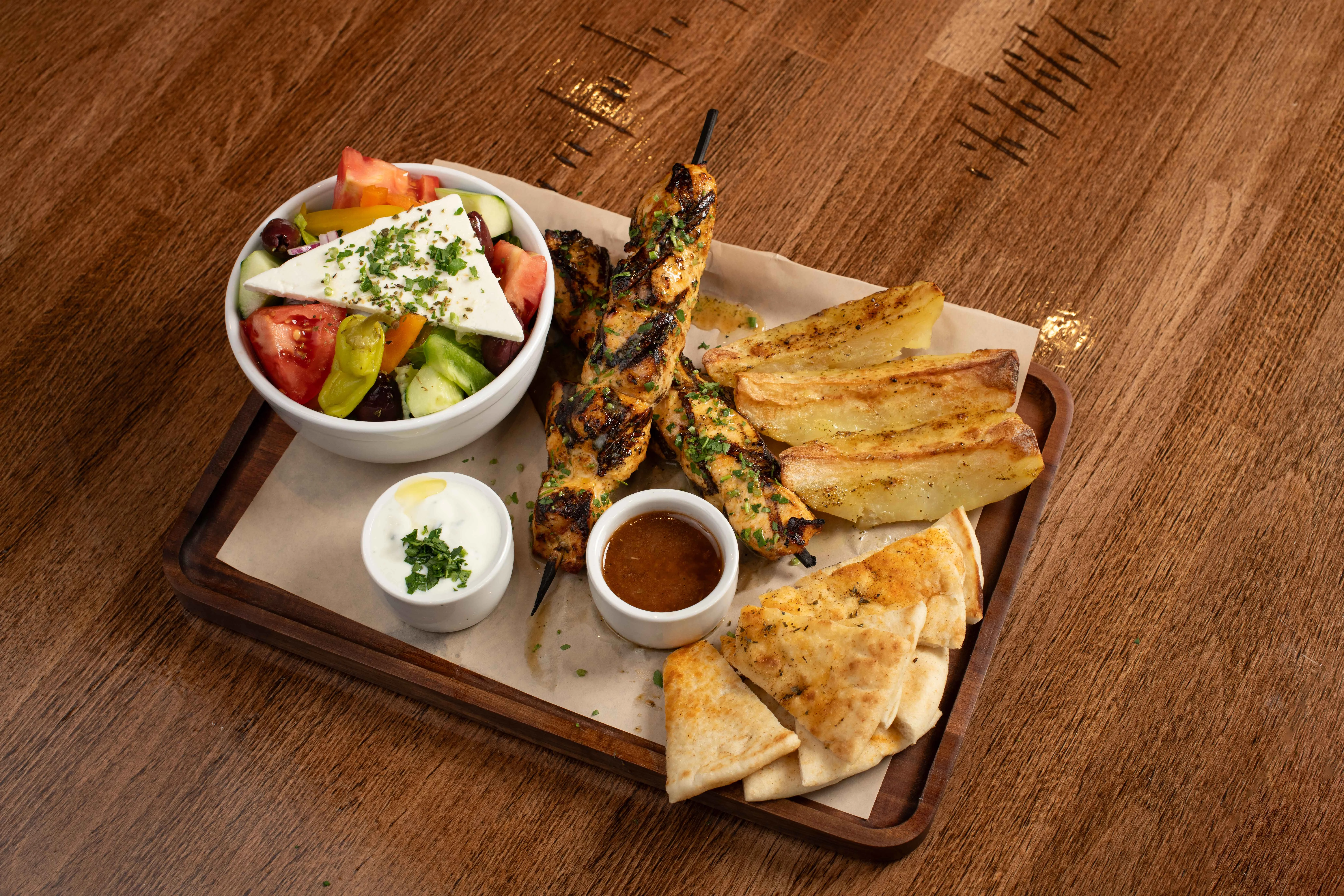 Grilled chicken skewers with Mediterranean salad and pita bread