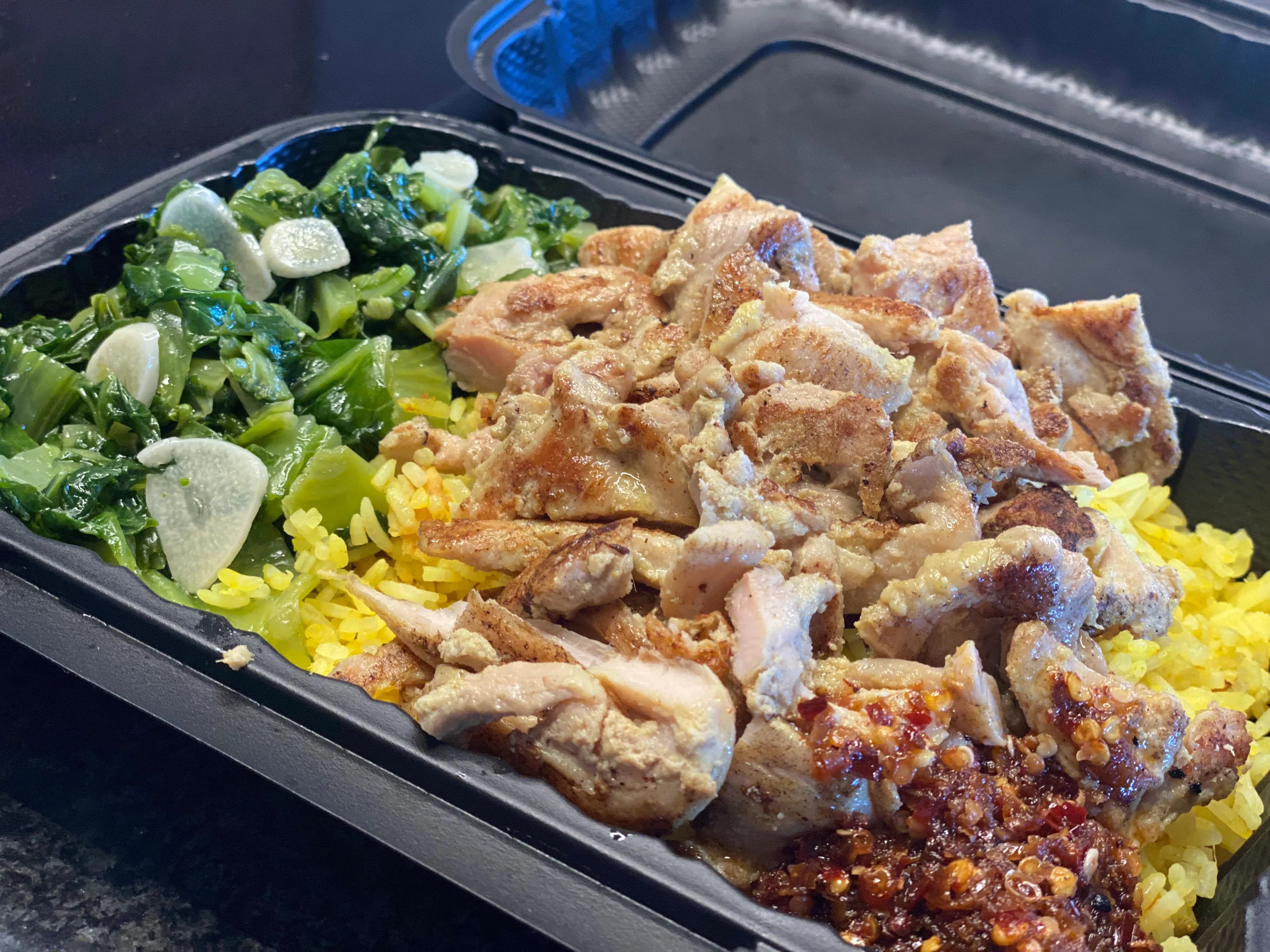 Savory chicken over yellow rice with sautéed greens