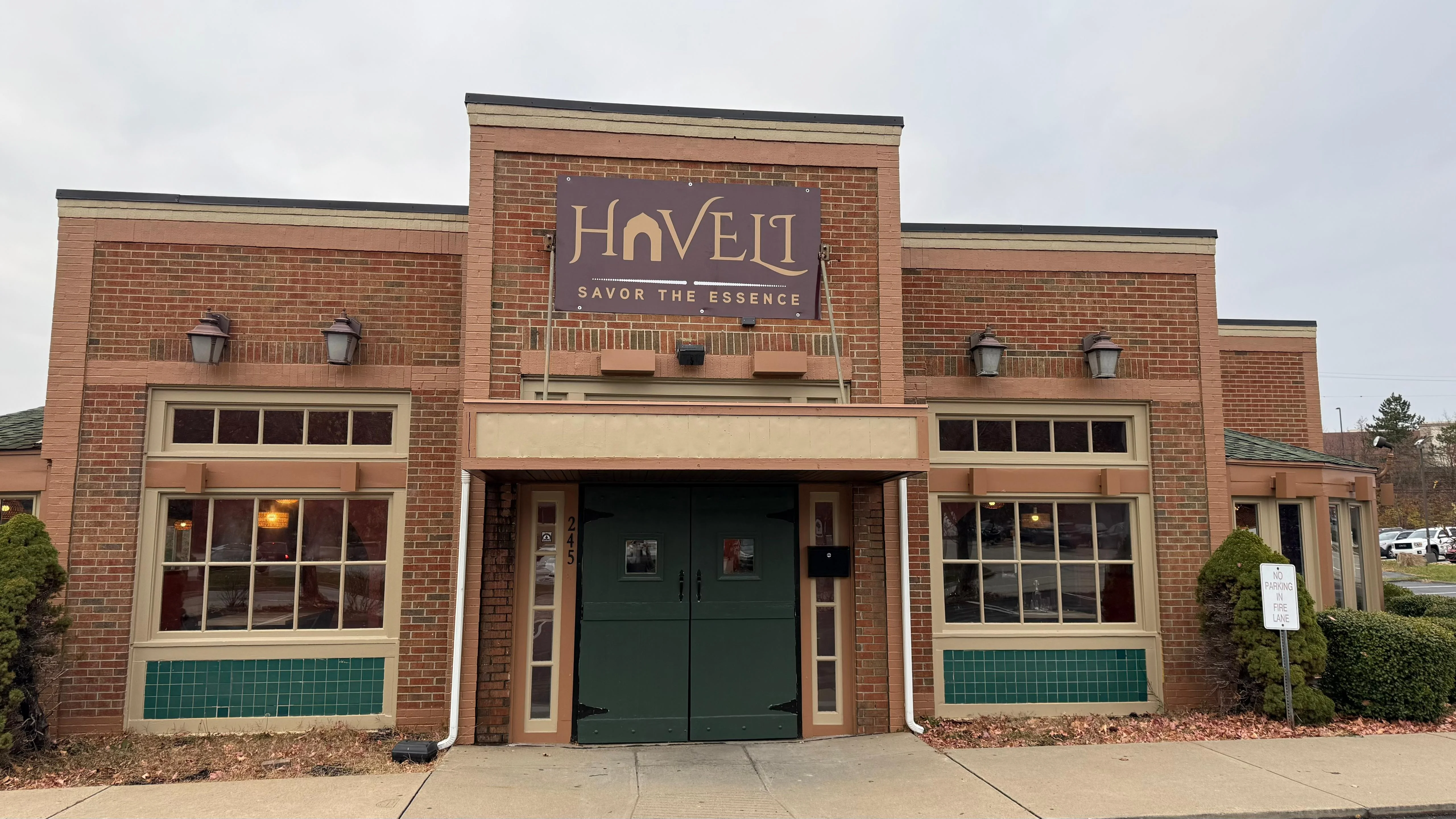 The exterior view of a restaurant building with a prominent sign indicating its name. The architecture features brick walls and large windows, giving a welcoming appearance.