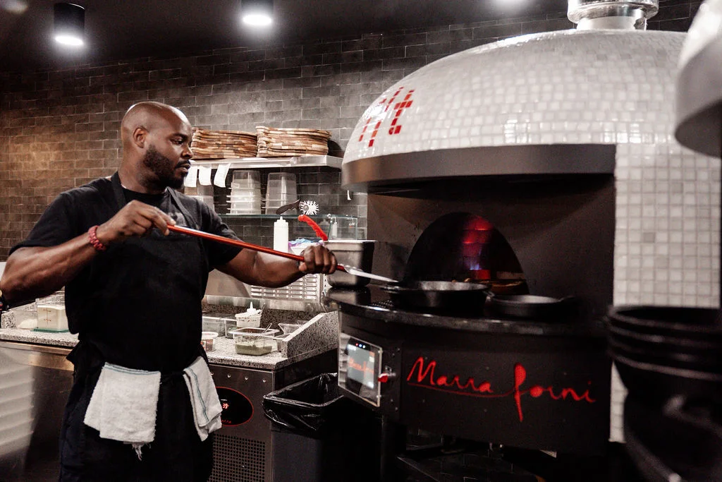 Chef using a pizza peel in a wood-fired oven