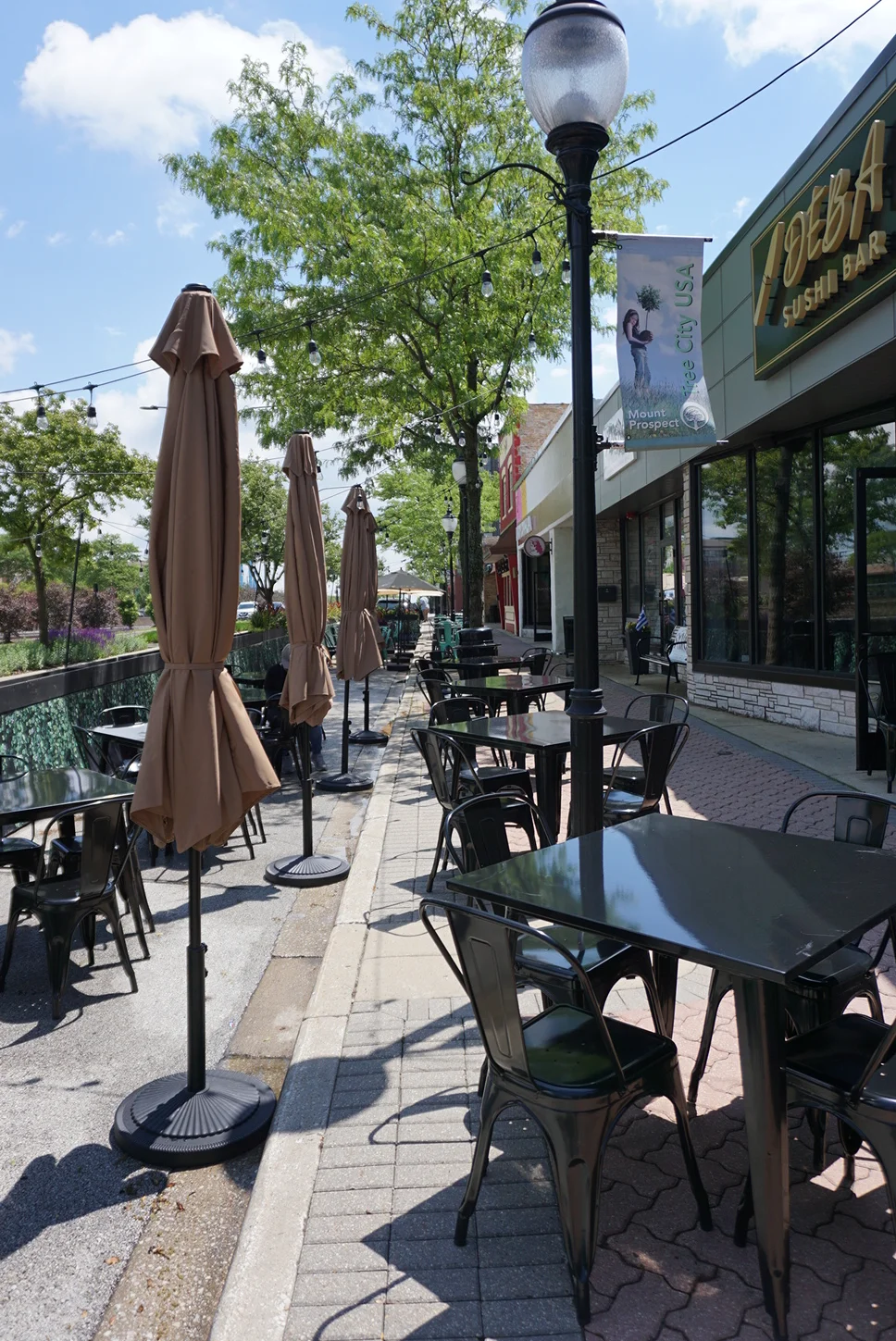 Outdoor dining area with tables and umbrellas at a sushi restaurant.