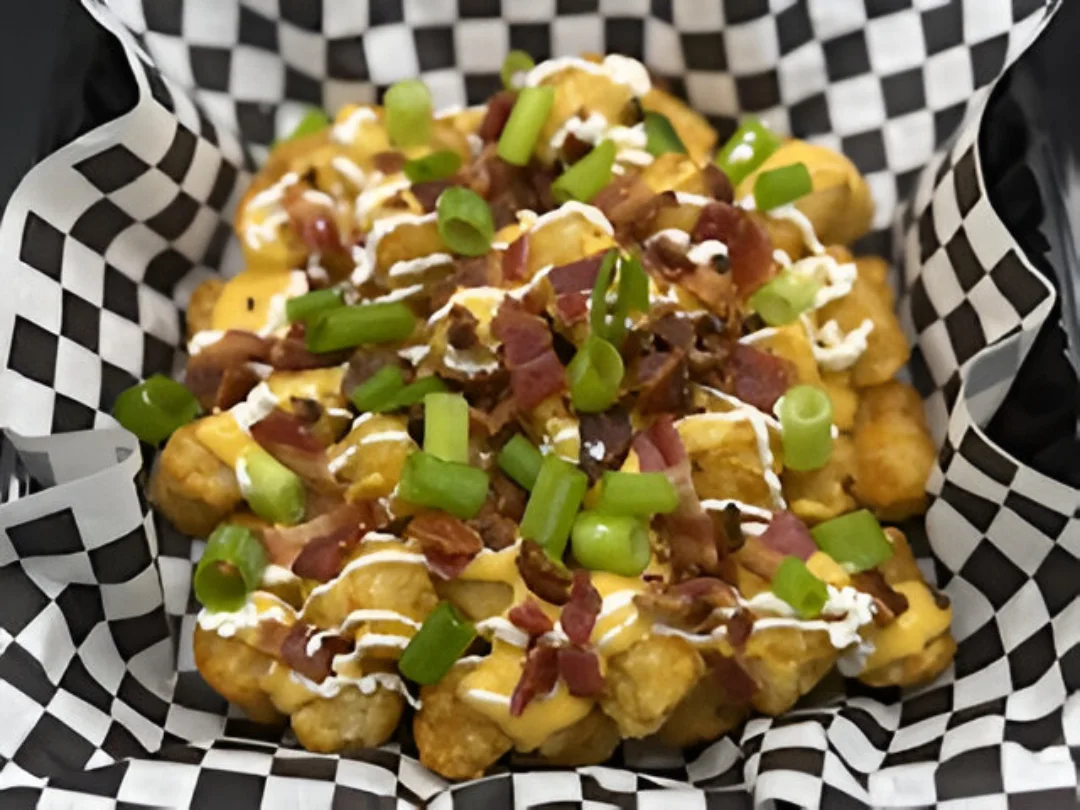 A loaded backed potato with  several toppings, including tater tots
