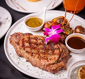 Grilled ribeye steak with sauces and garnishes