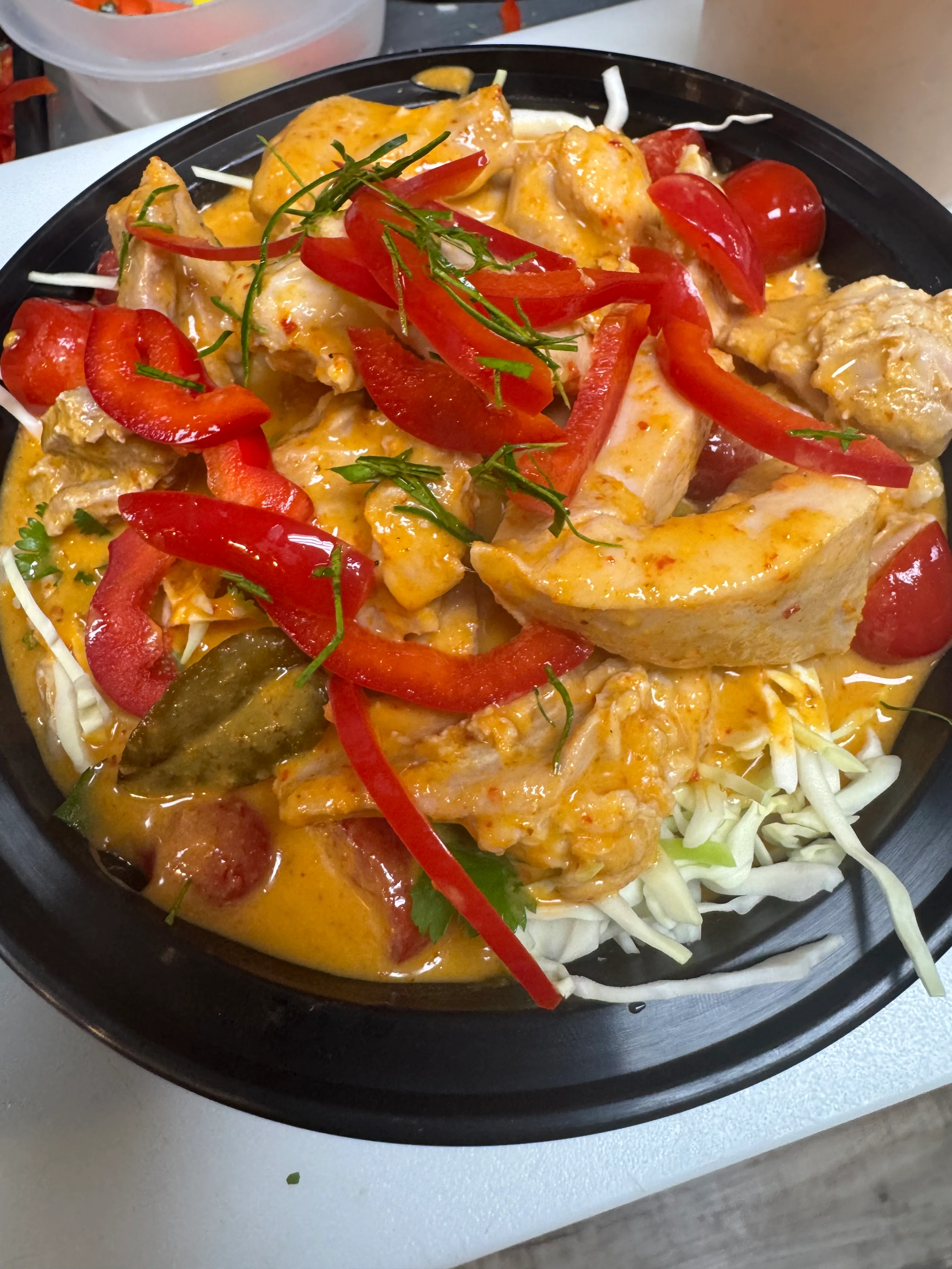 Thai red curry chicken served with fresh vegetables and herbs