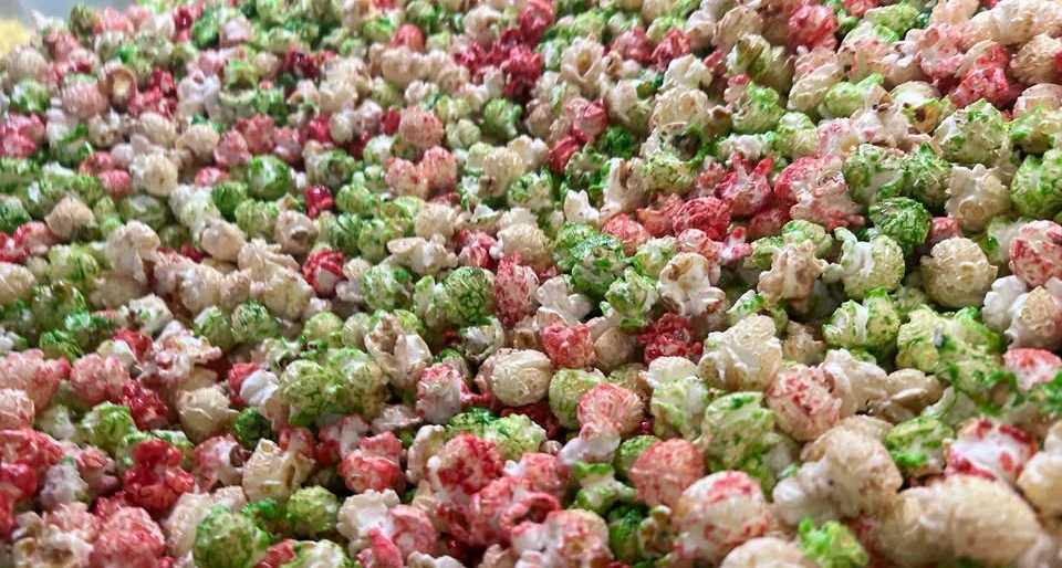 A container of barbecue-flavored popcorn, set against a background of popcorn kernels.