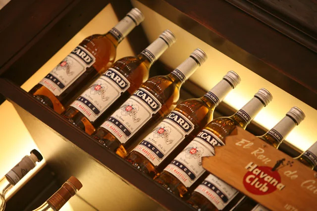 Display of Ricard bottles on a wooden shelf in a bar setting