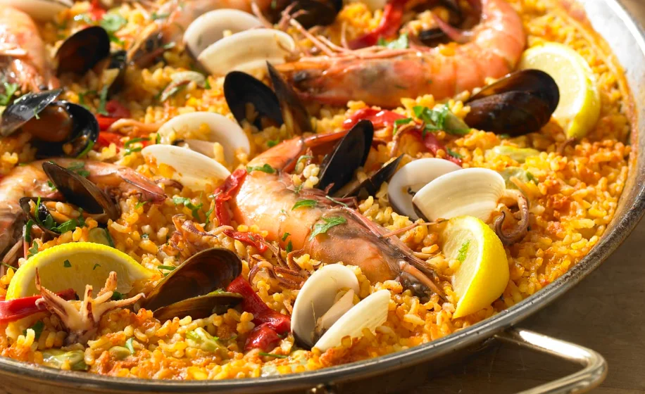 A vibrant paella dish with seafood and vegetables served in a traditional pan.