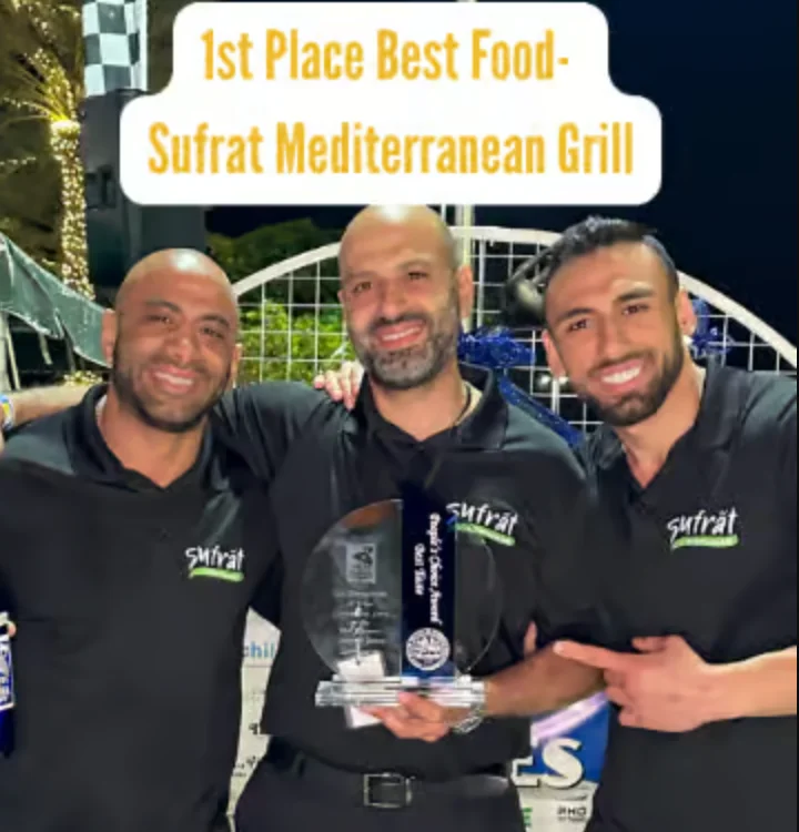 Three smiling men holding a glass award plaque, the founders of sufrat in black branded sufrat shirts.