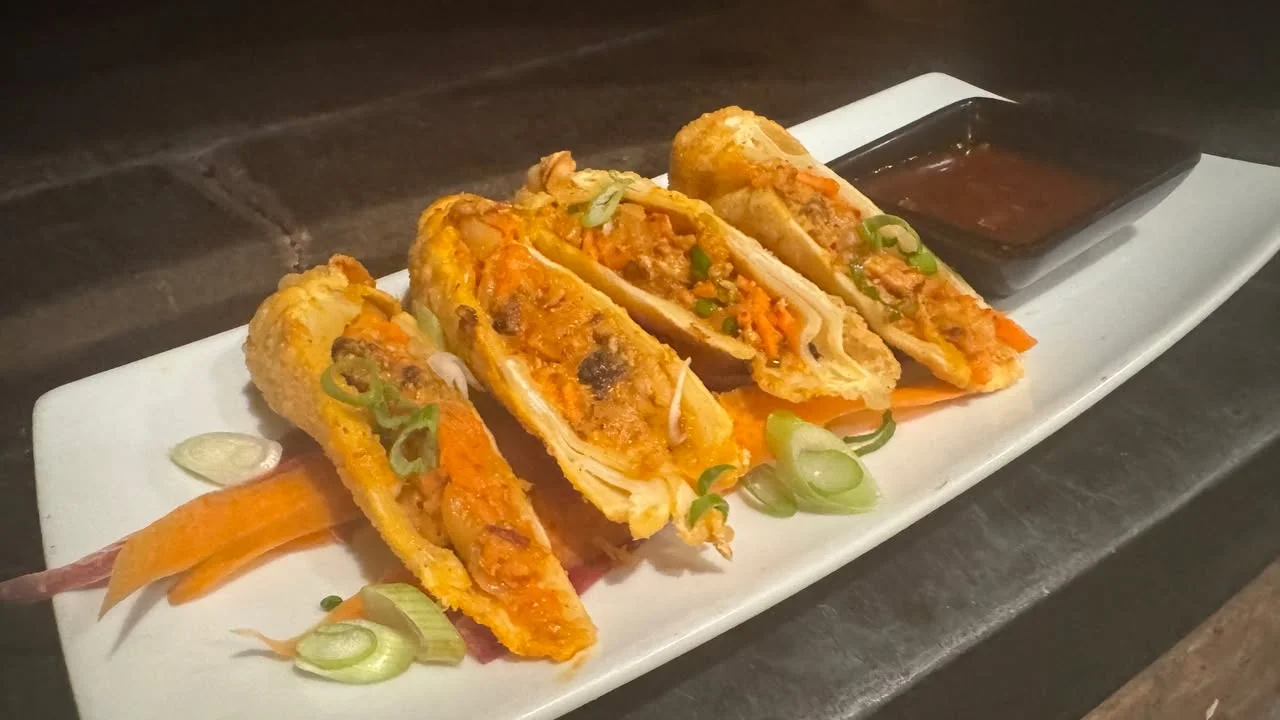 Crispy egg rolls sliced and served with dipping sauce and scallions