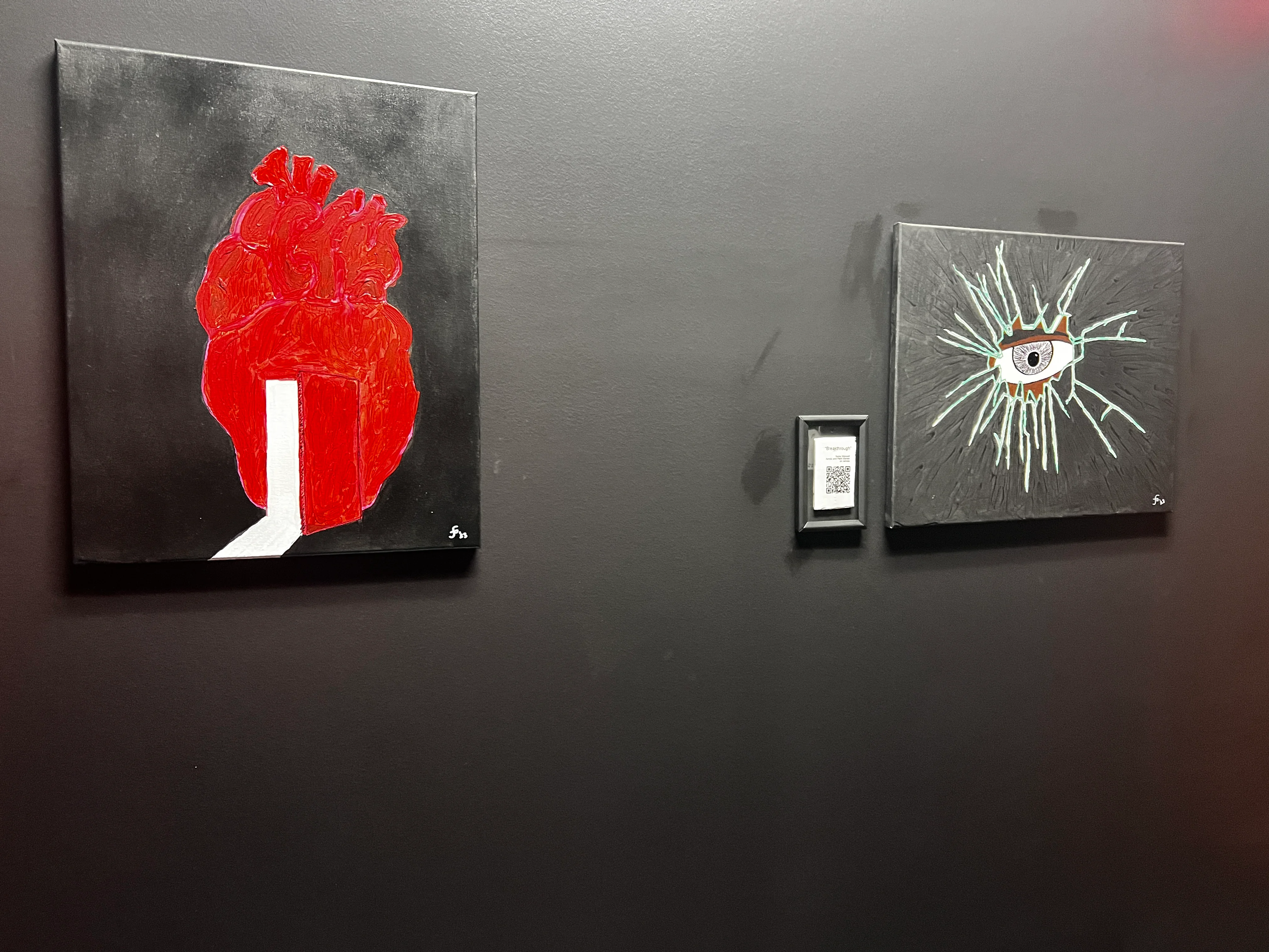 Contemporary art pieces featuring a heart and an eye on a dark wall