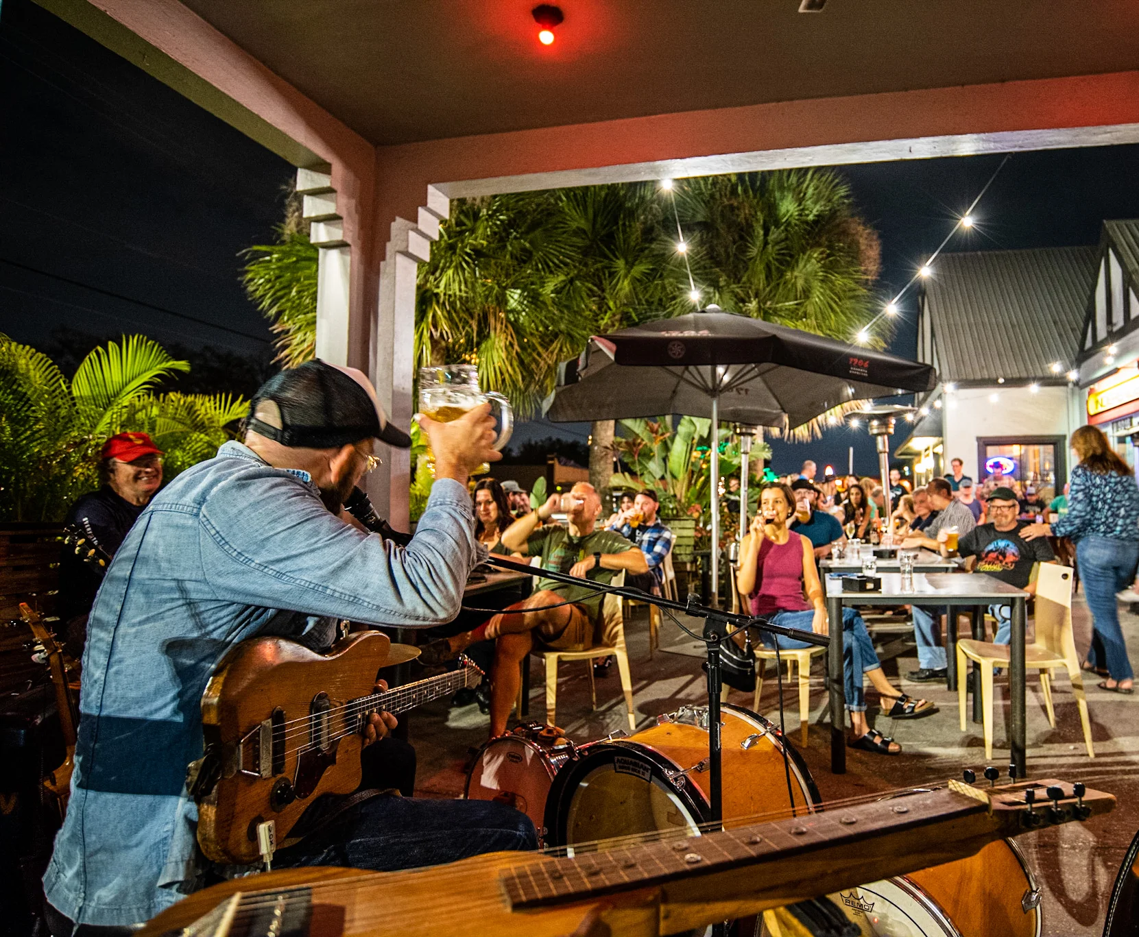 Live music performance at a vibrant outdoor restaurant with a lively crowd.